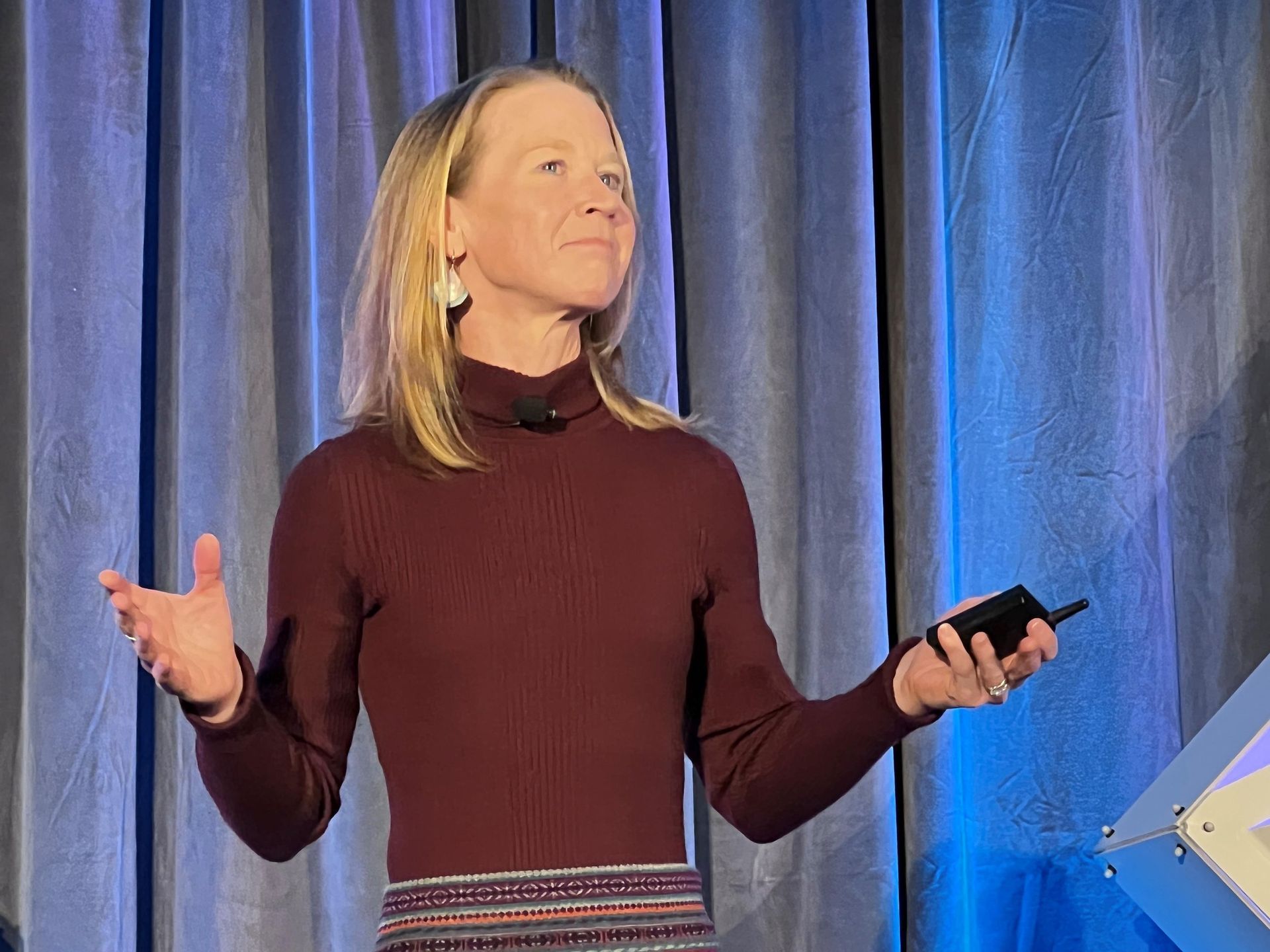 April Rinne is standing on a stage holding a cell phone.
