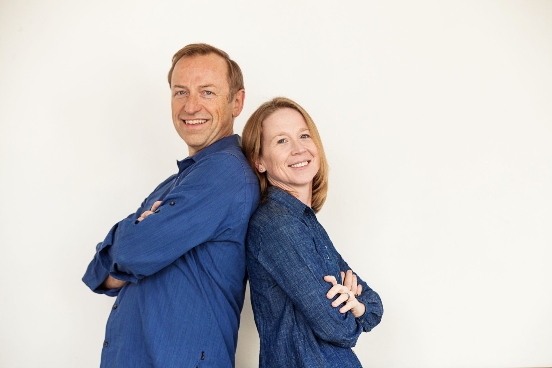 Jerry Michalski and April Rinne are standing back to back with their arms crossed.