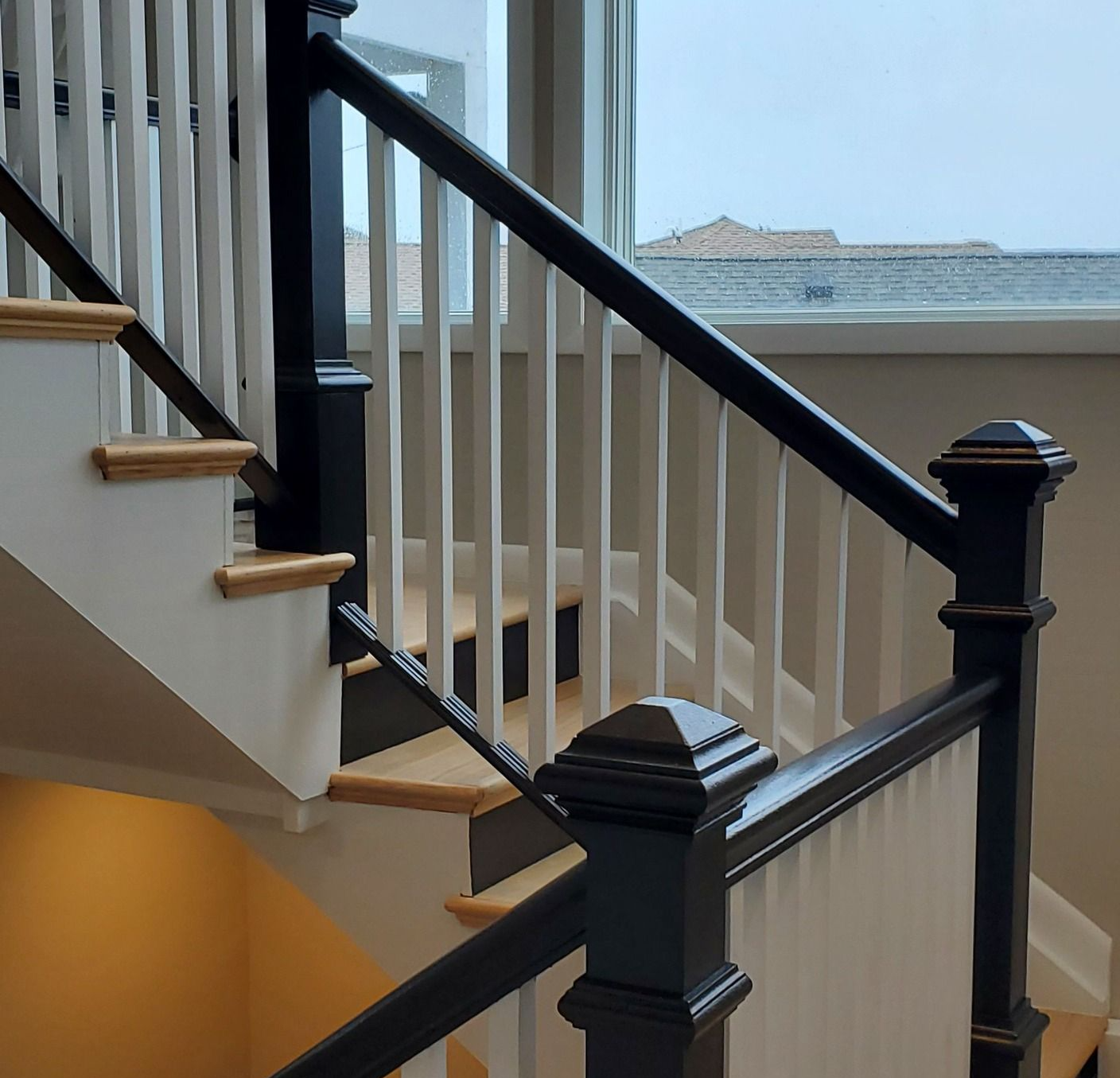 Staircase with black handrail and white balusters. Wood steps.