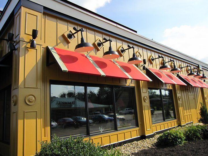 Restaurant exterior with gold siding, red awnings, and large windows.