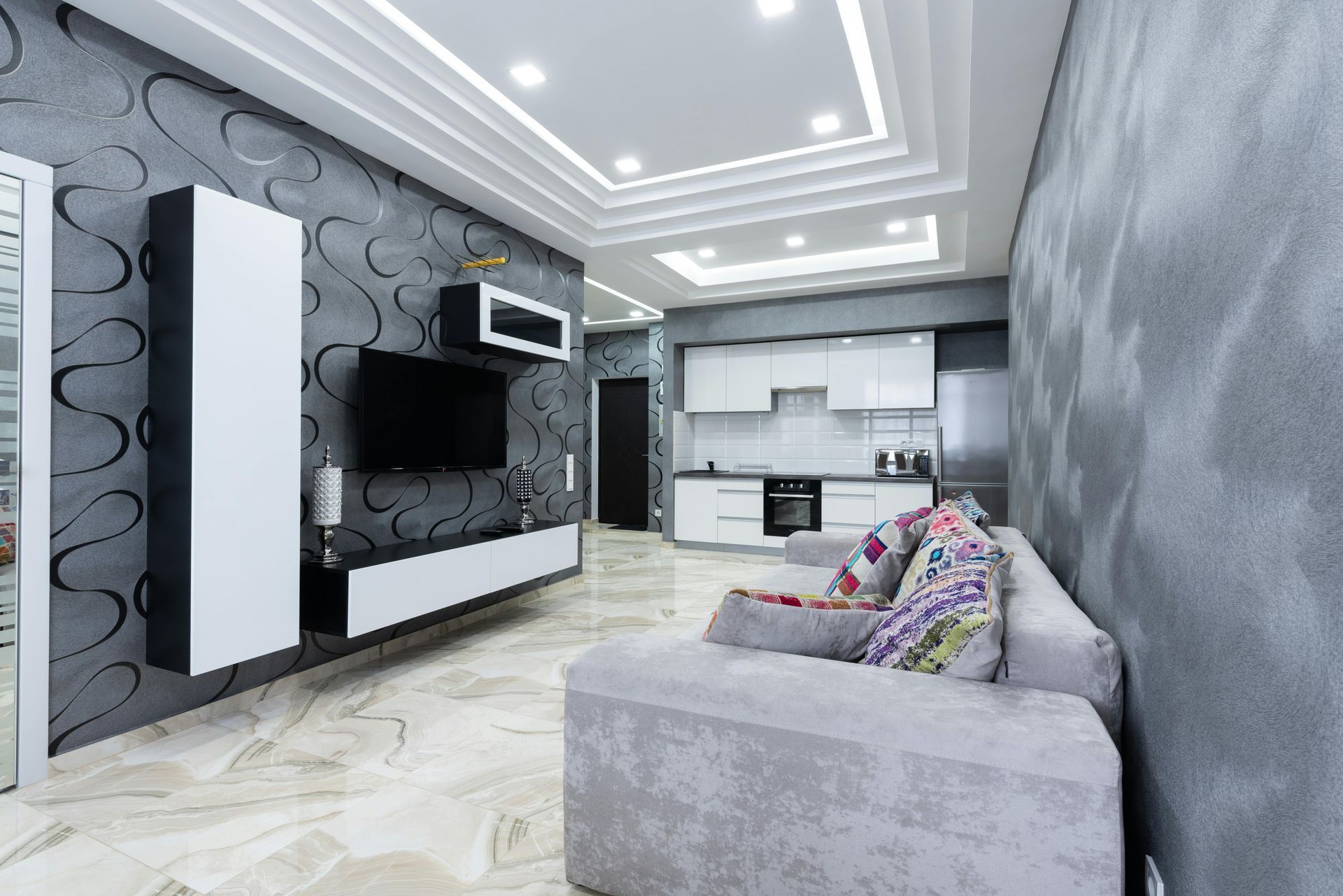 Modern living room with gray walls, white cabinets, and a gray sofa.