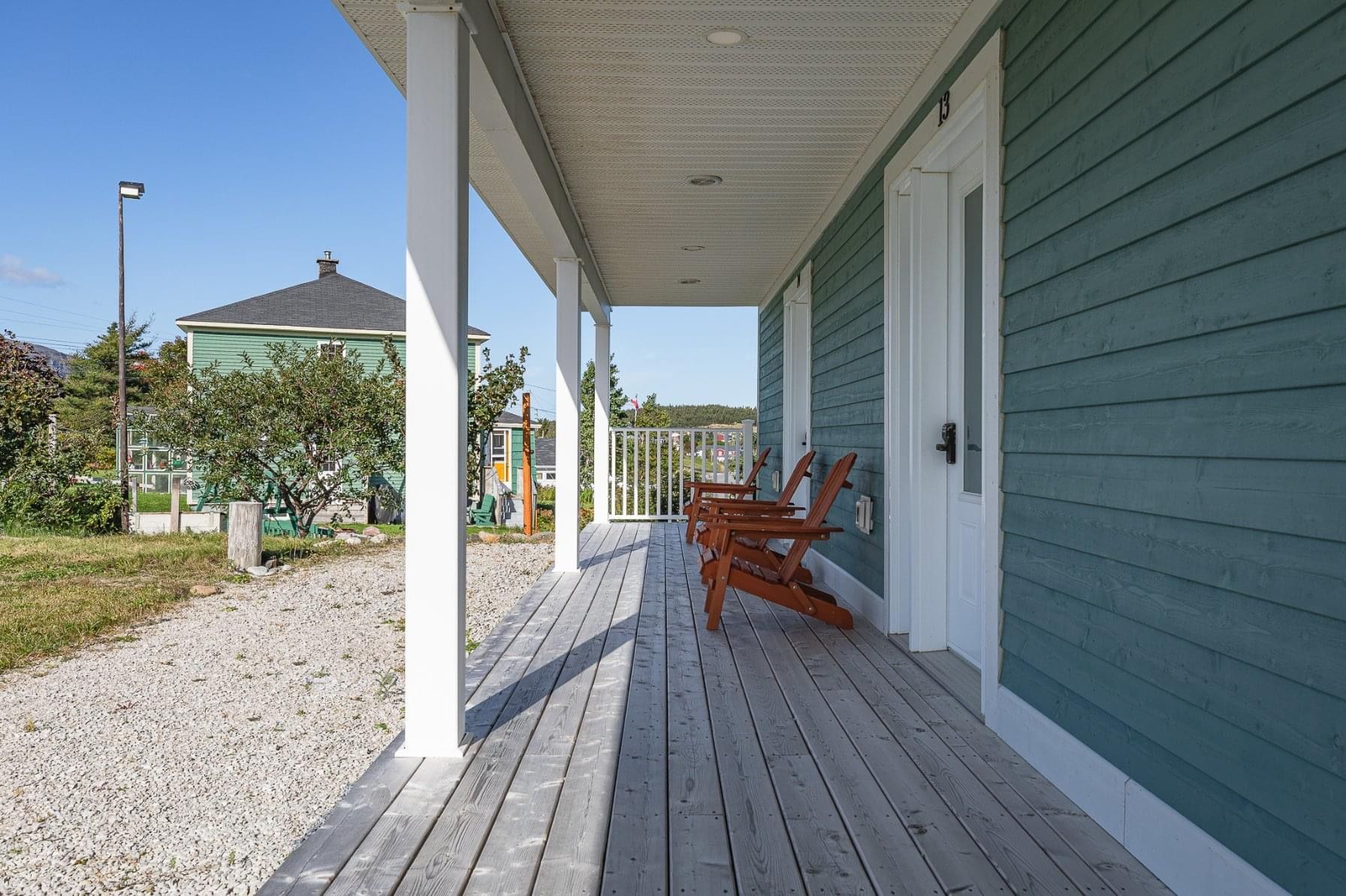 A porch with chairs and a blue house in the background