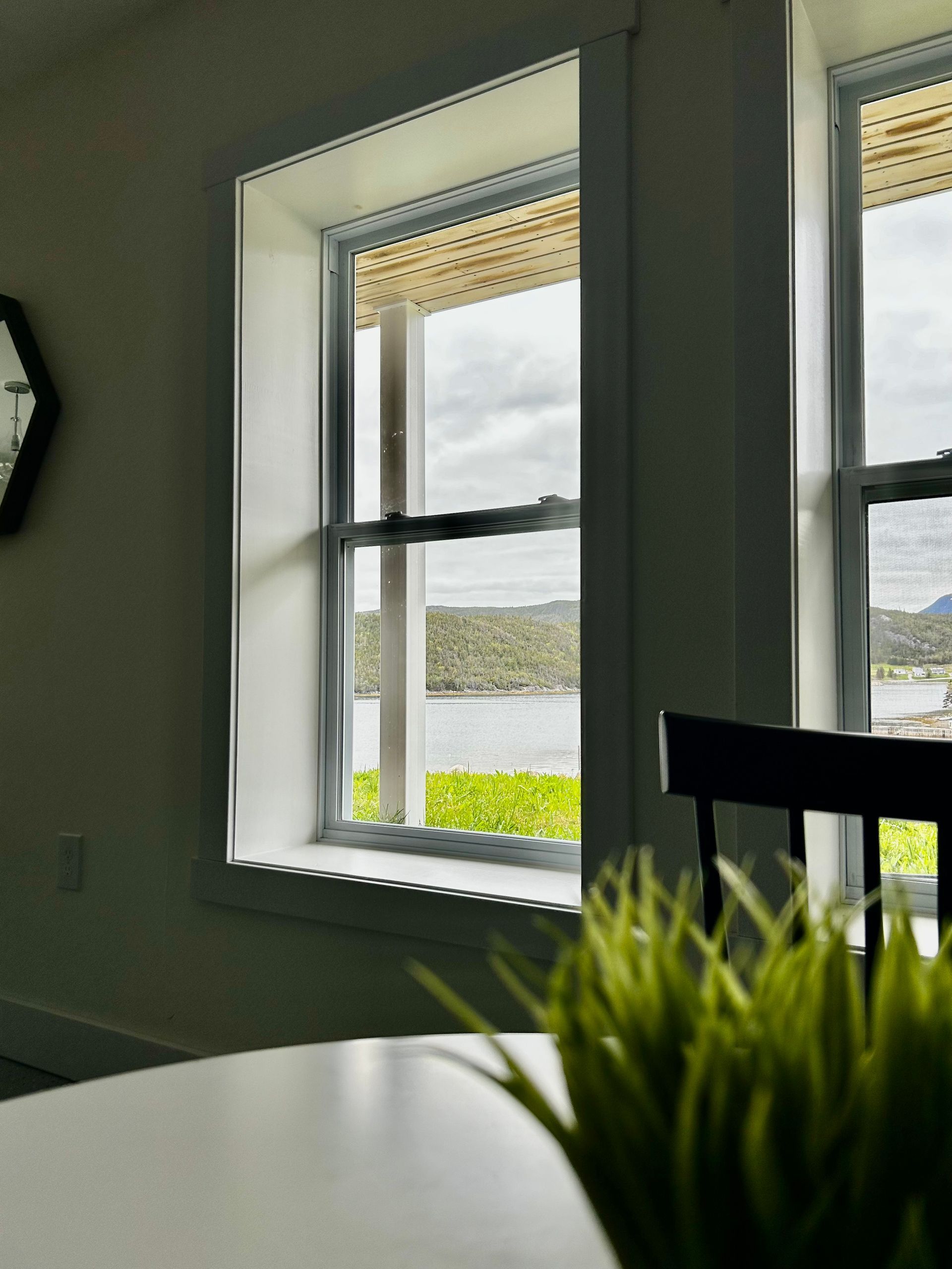 A clock hangs above a window with a view of a lake