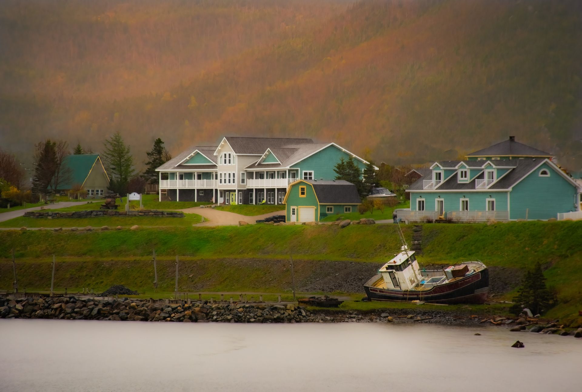 A boat is docked in front of a house on the shore of a lake.