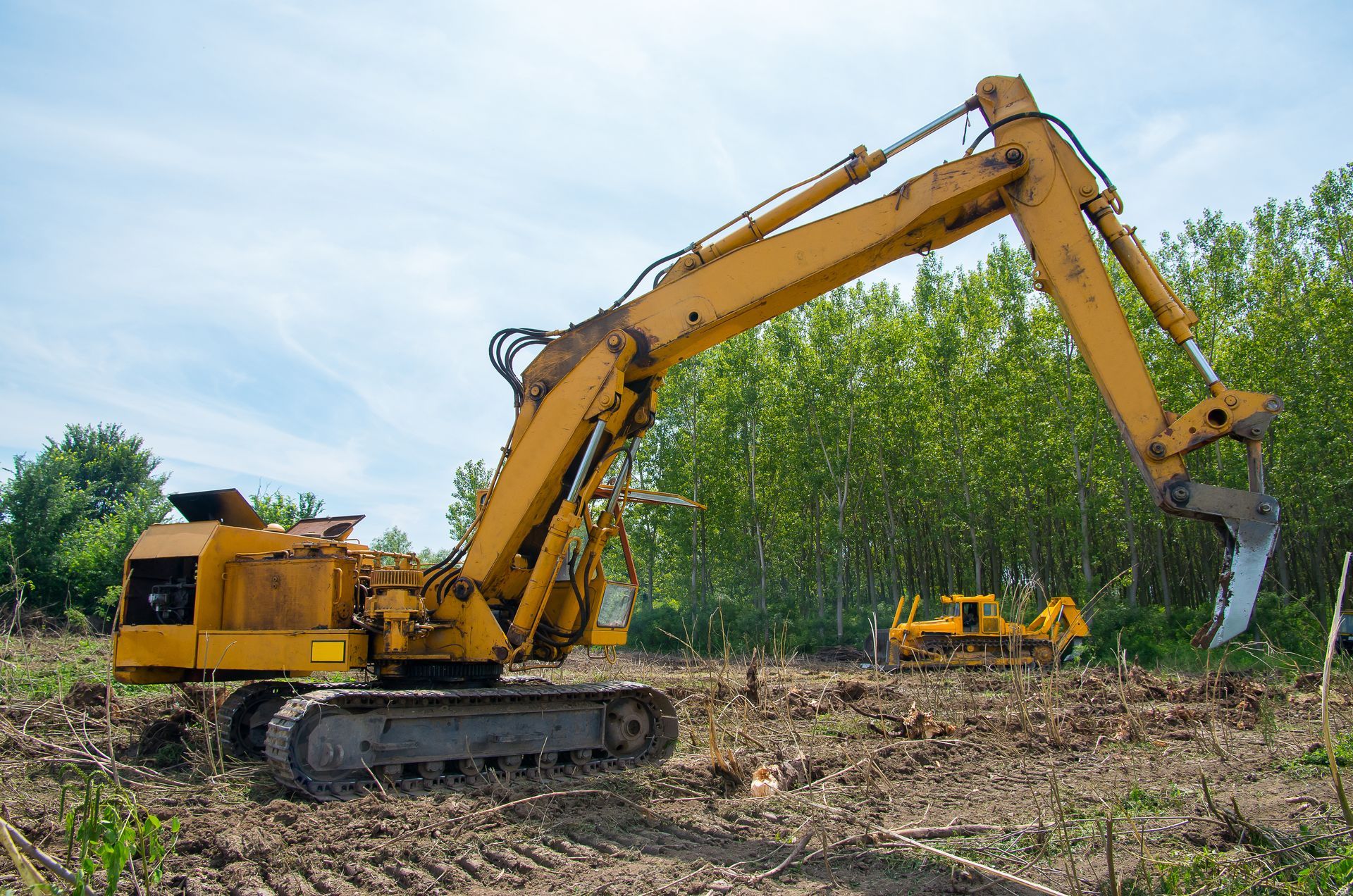 A large yellow excavator is sitting in a dirt field.