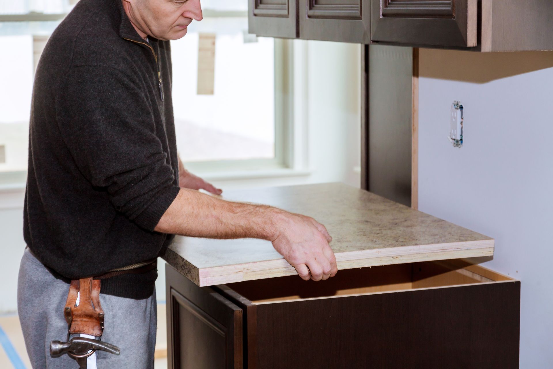A man is installing a counter top in a kitchen