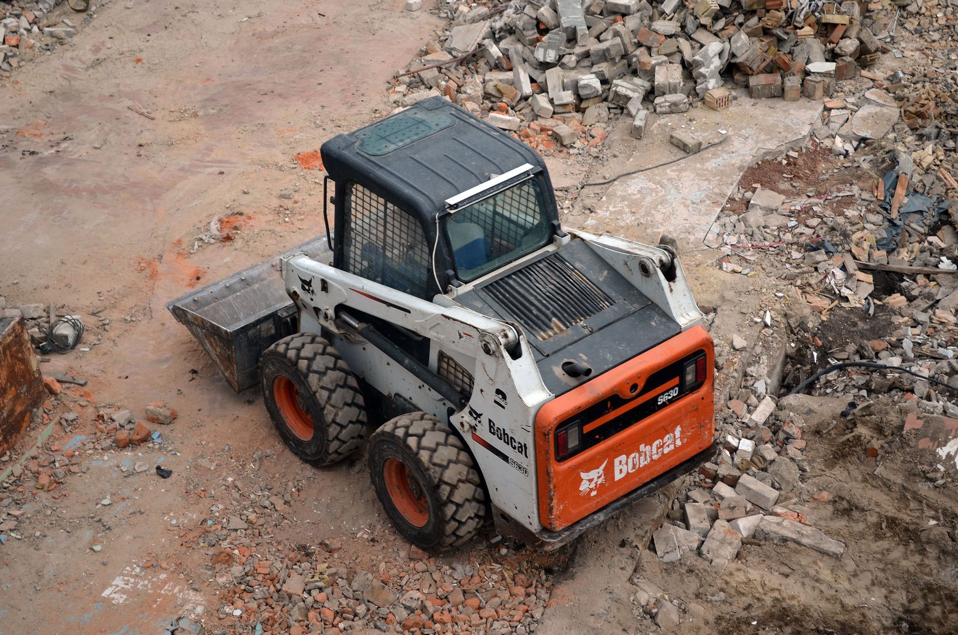 A bobcat skid steer is sitting in a pile of rubble.