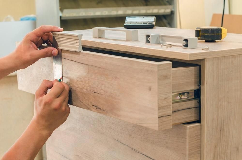A person is opening a drawer on a wooden dresser.