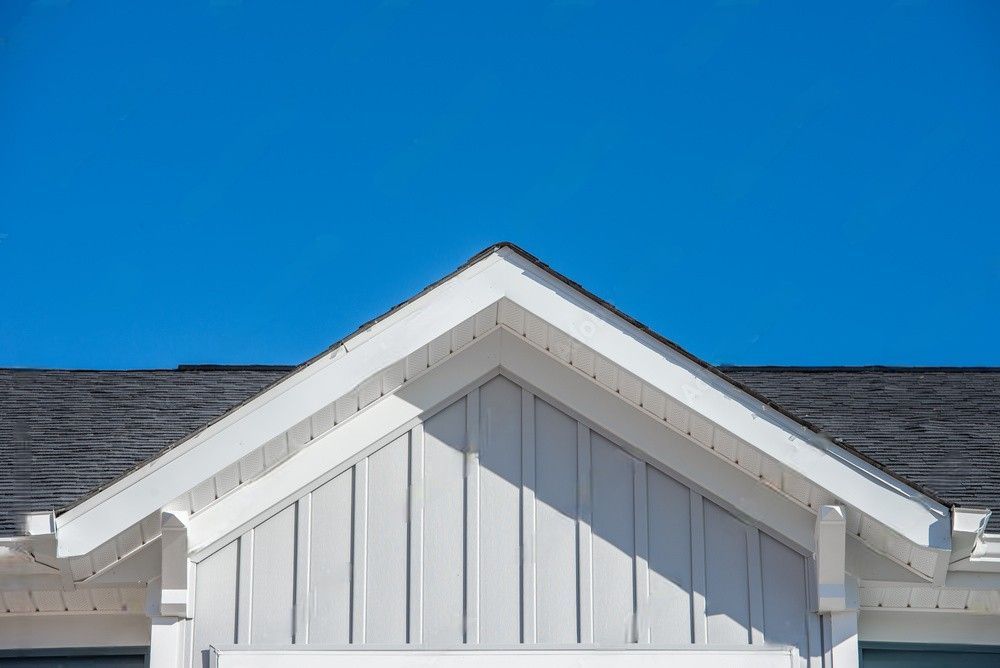 The roof of a white house with a blue sky in the background.