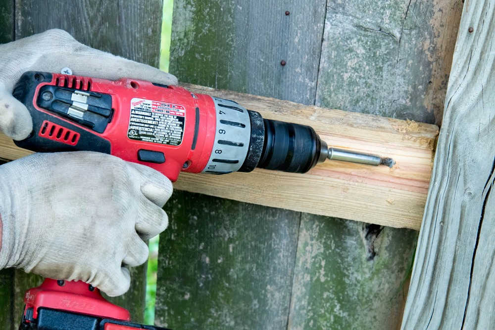 A person is using a drill to drill a hole in a piece of wood.