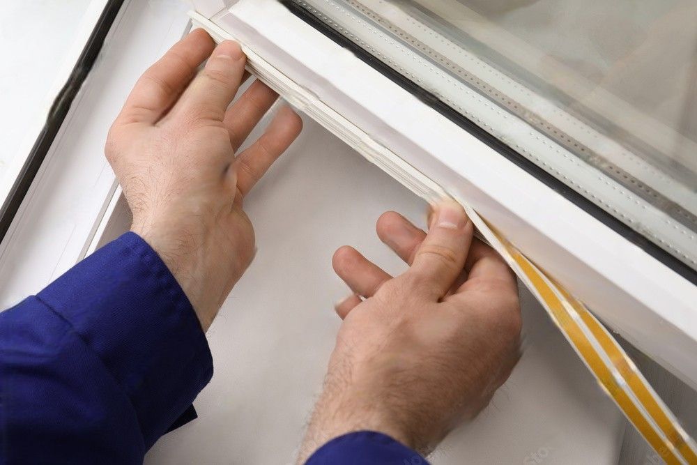 A person is holding a piece of tape over a window.