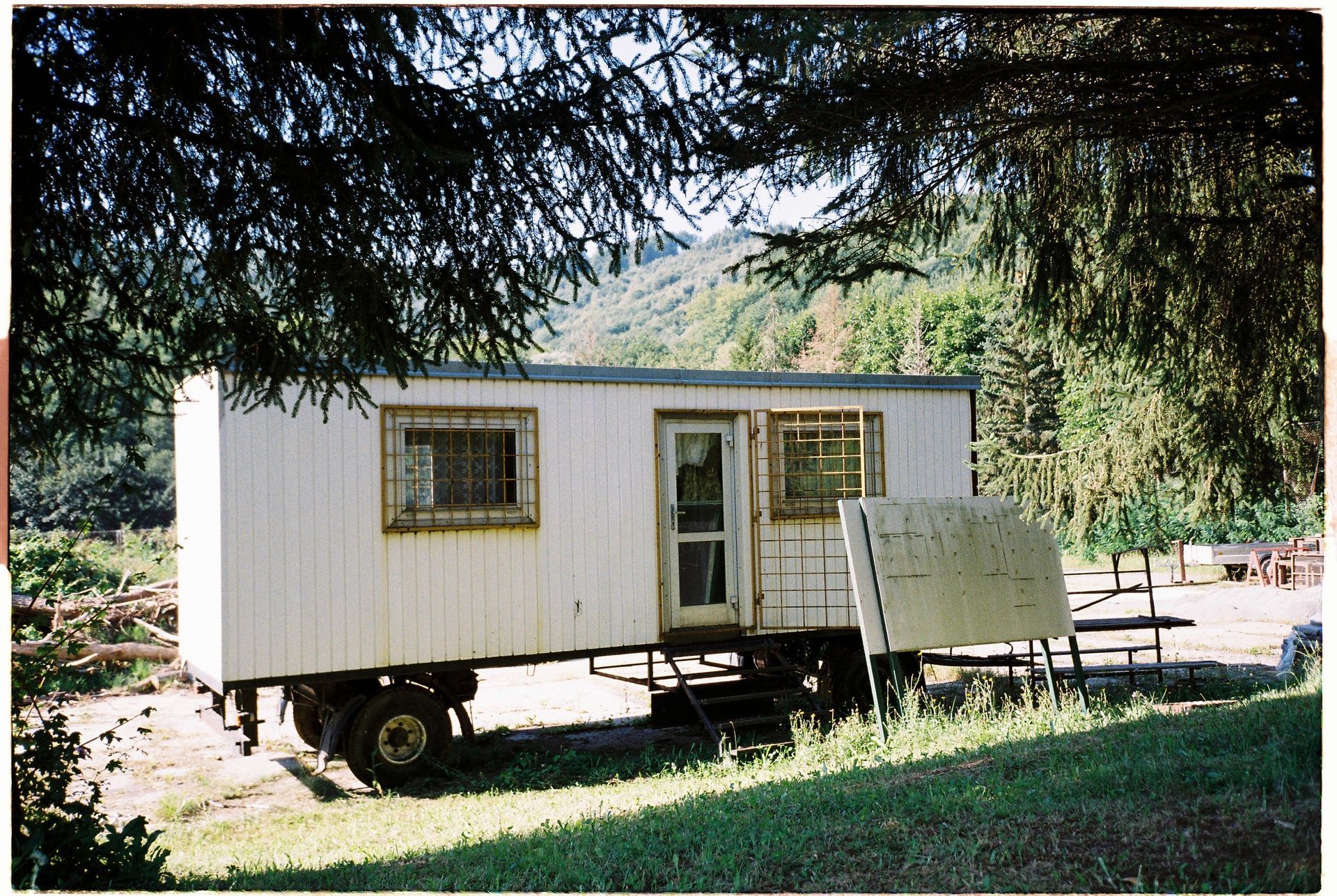 A white trailer is parked in a grassy field