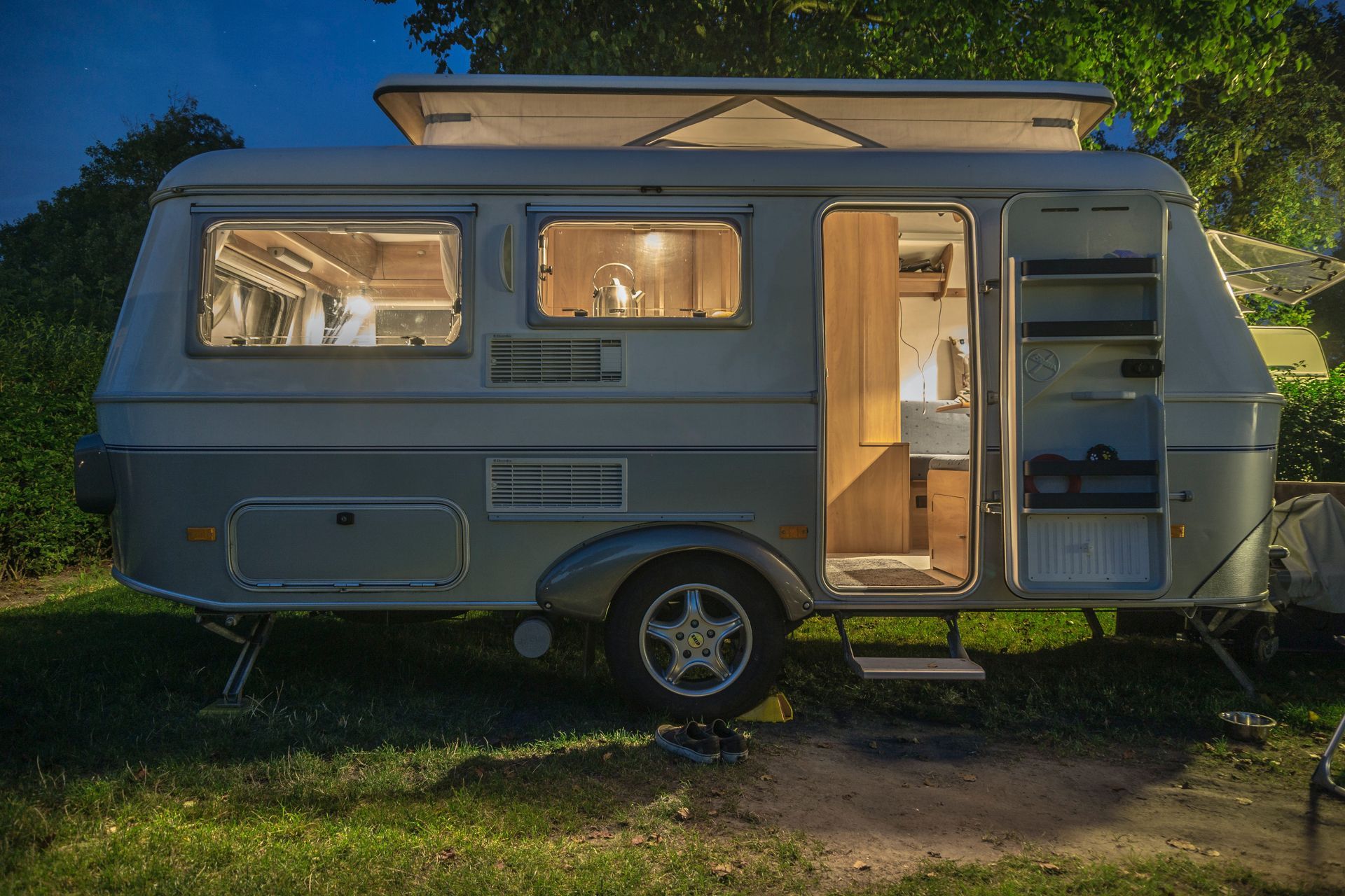A camper trailer is parked in a grassy field at night.