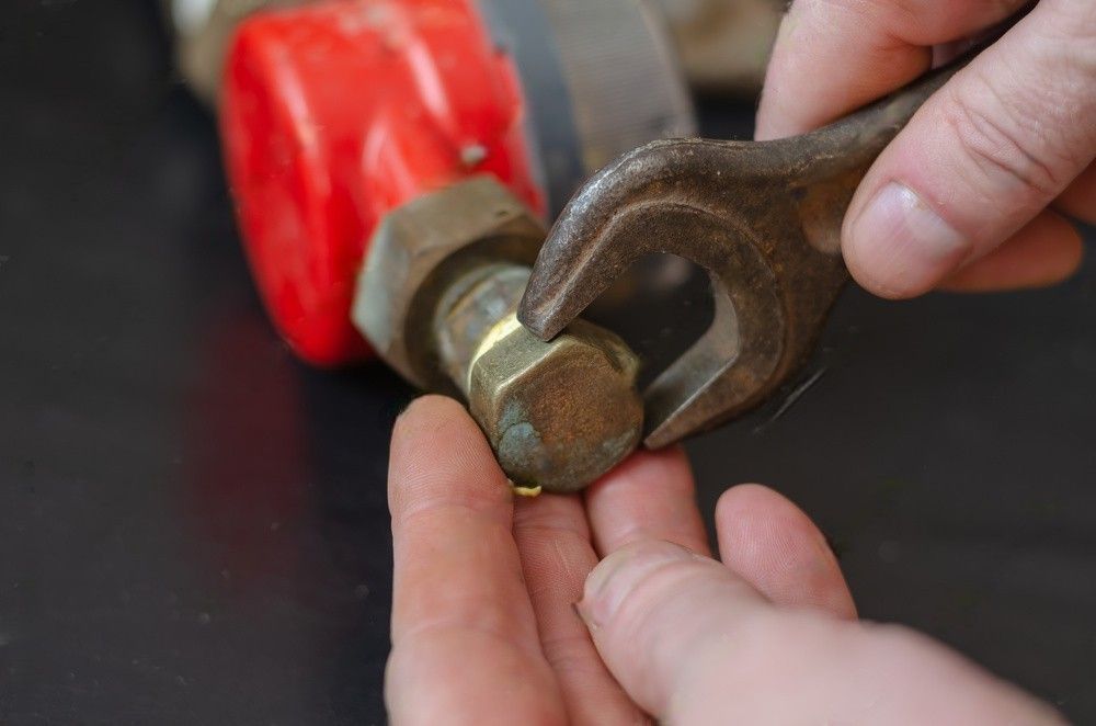 A person is holding a wrench and a nut in their hands.
