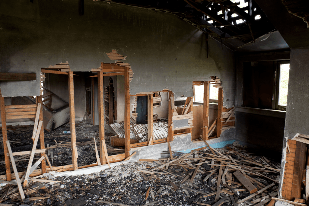 The inside of an abandoned building with a lot of wood and a lot of rubble.