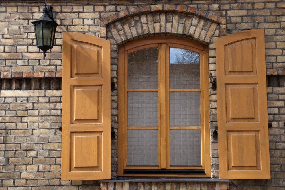 A window with wooden shutters on a brick wall