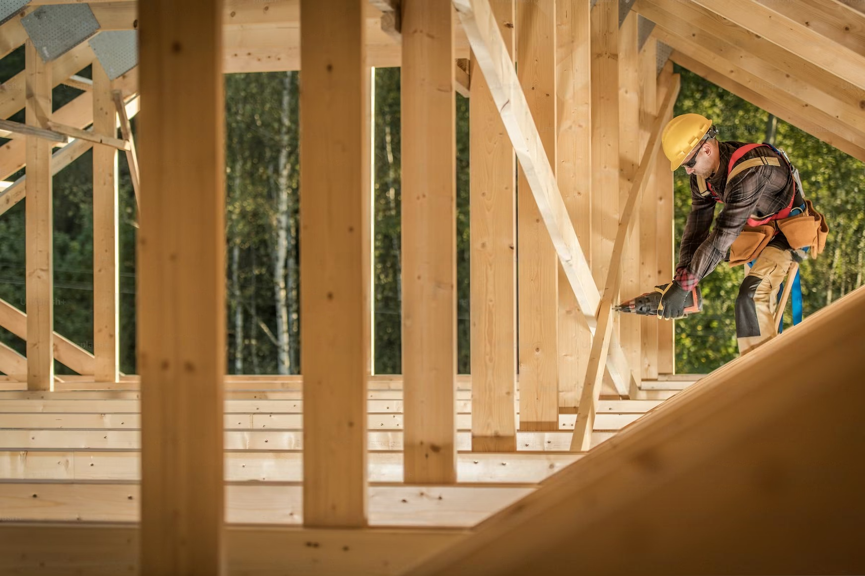 A construction worker is working on a wooden structure.