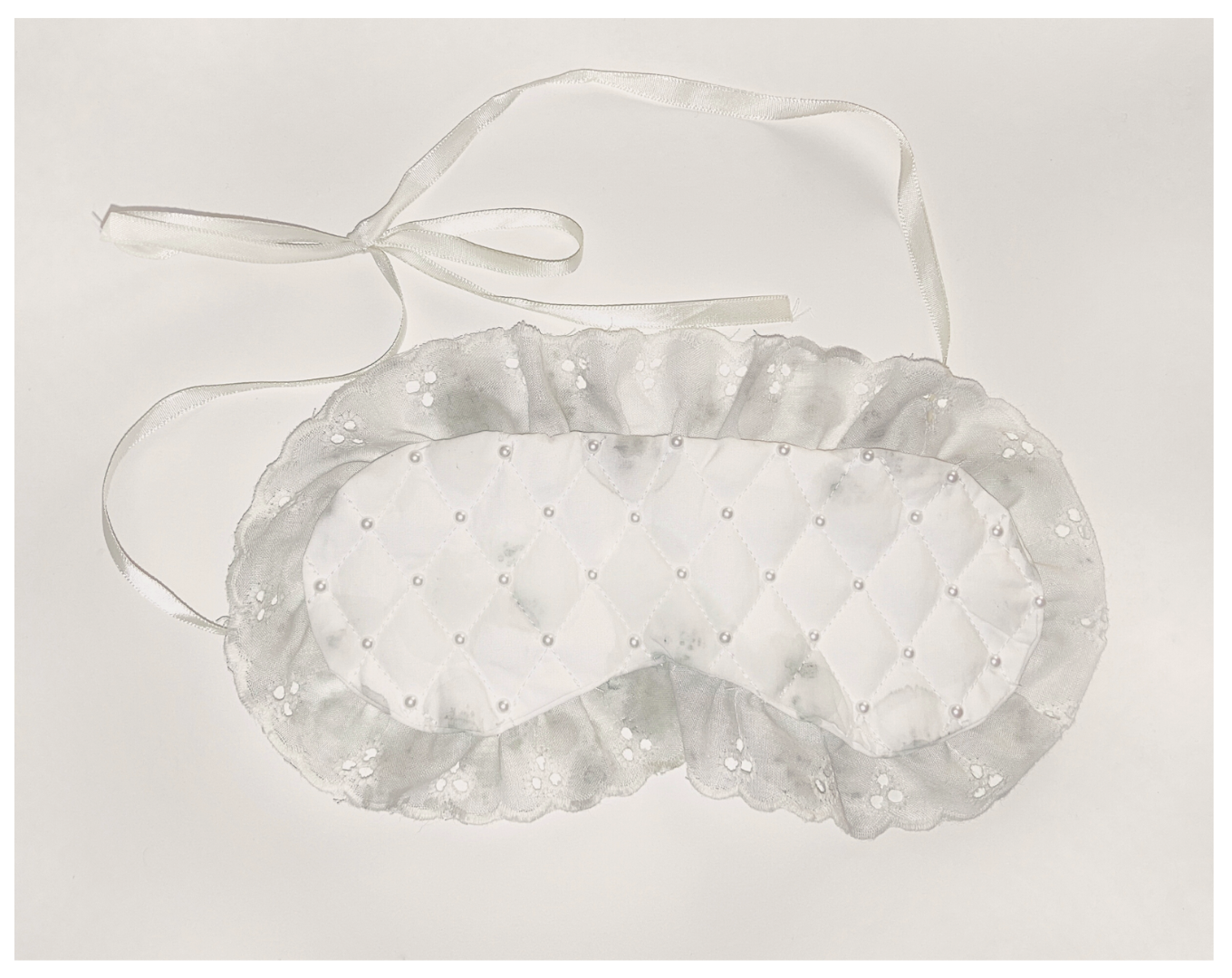 A white sleeping mask that has been stained by mold, from the work 