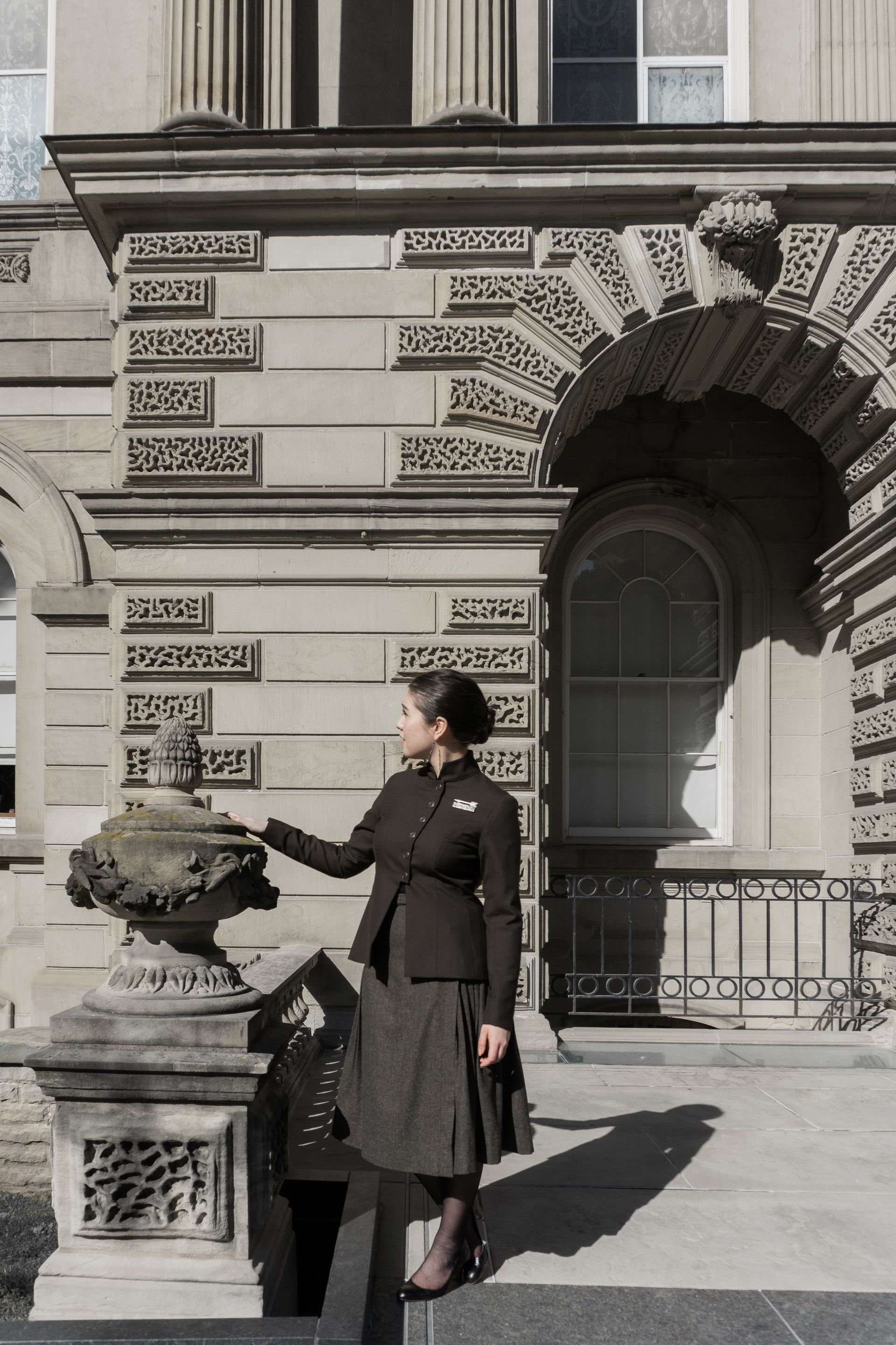 A woman in a suit looking off into the distance in front of a classical facade at Osgoode Hall.