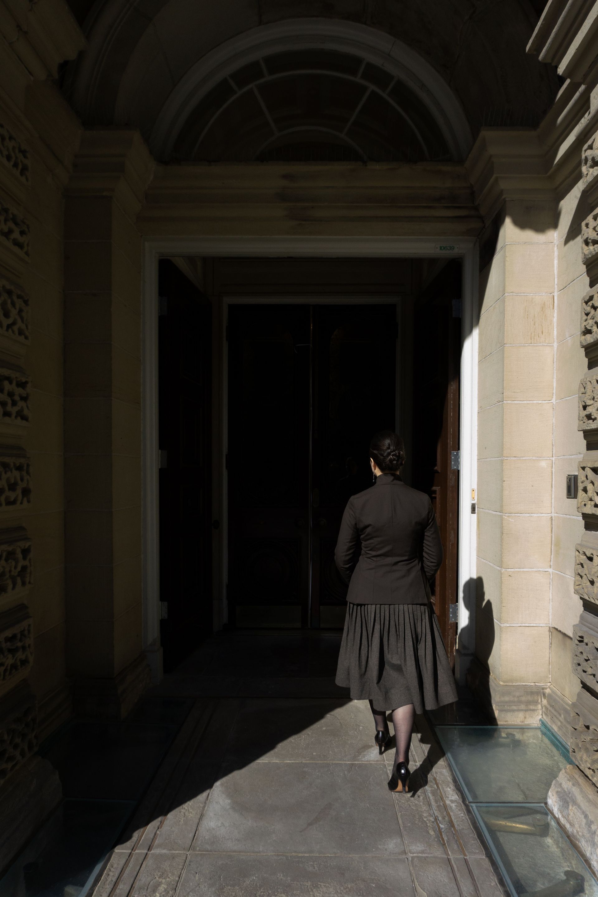A woman in a suit with her back turned walking towards the entrance of Osgoode Hall.