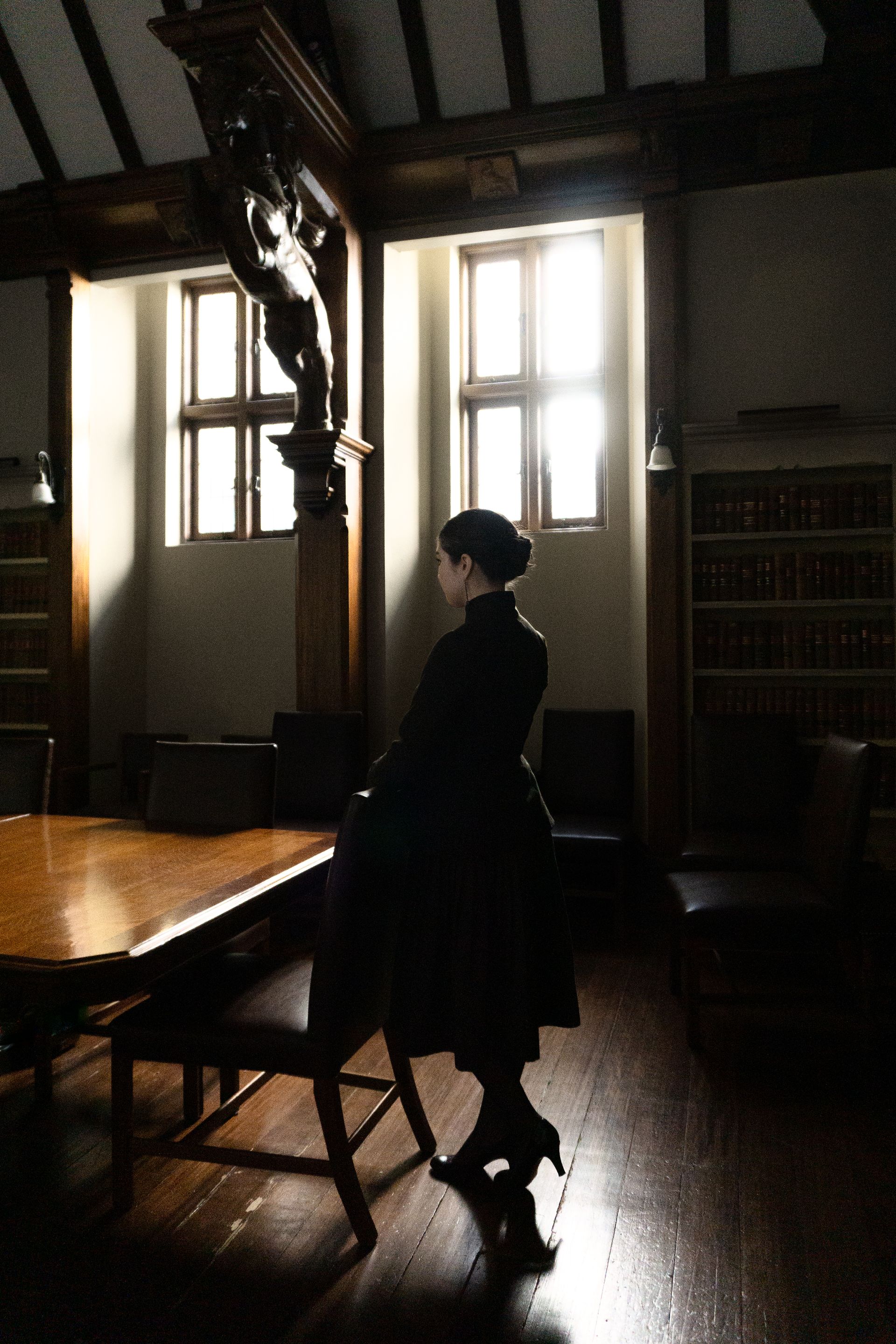 A woman in a suit standing in a dark office.