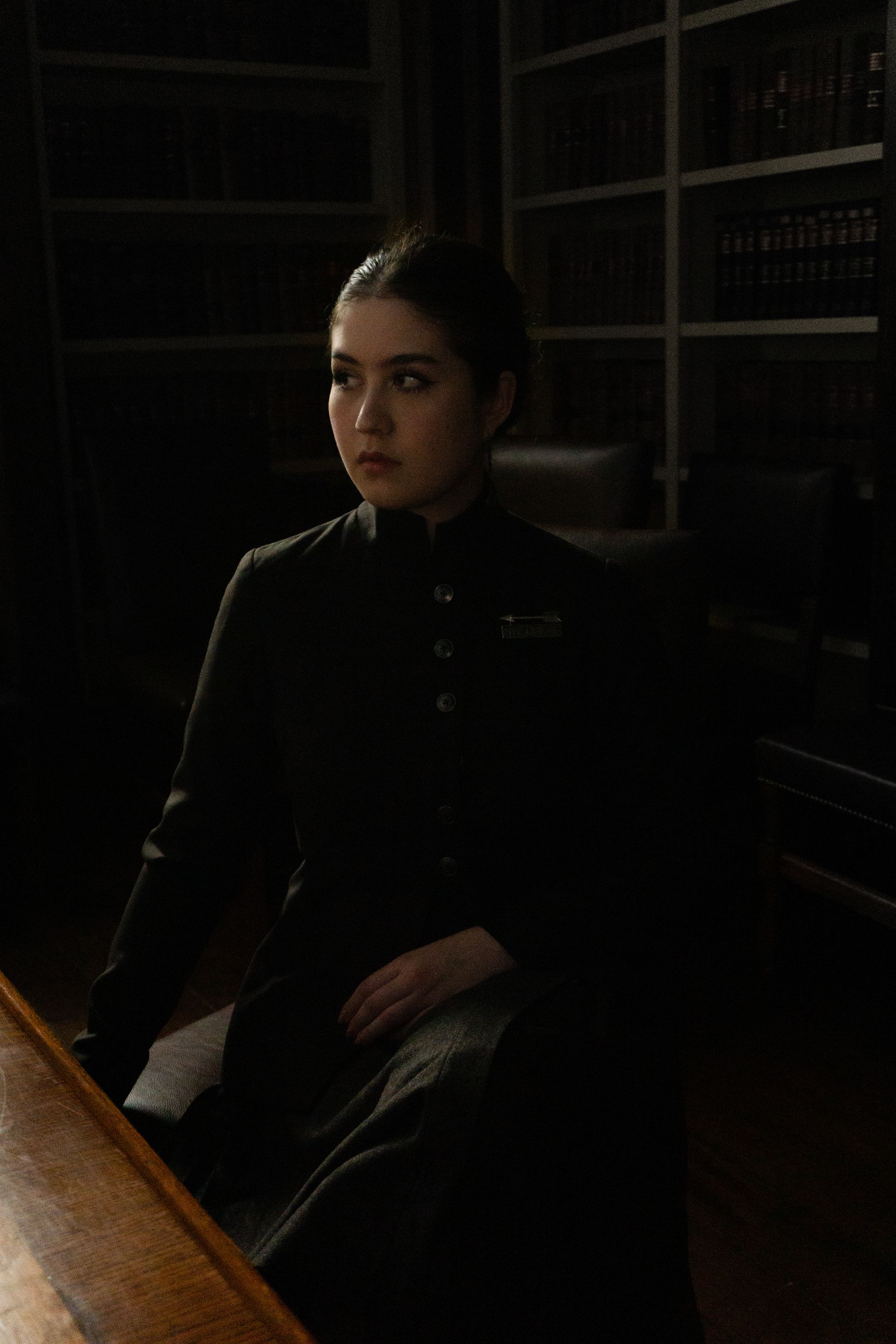 A woman in a suit sitting in a dark office.