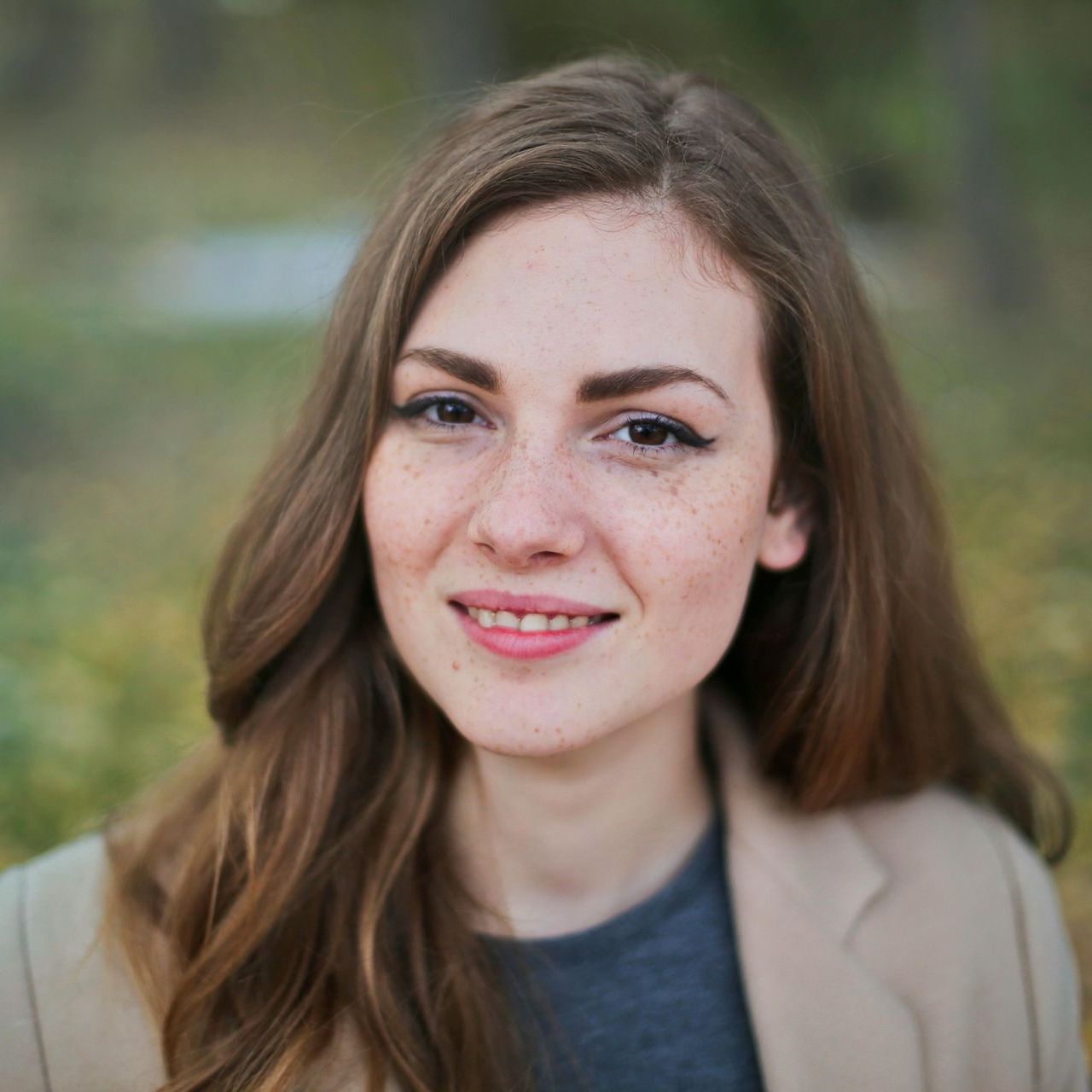 A woman with long brown hair and freckles is smiling for the camera.