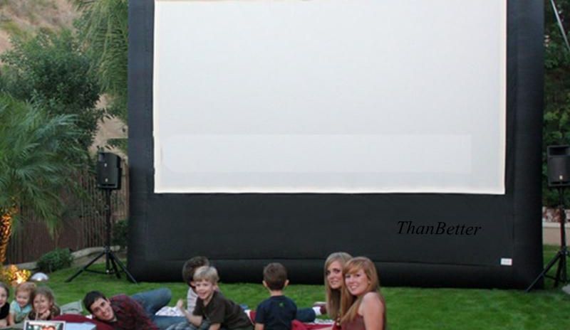 Large inflatable movie screen set up in a backyard, with a group of people sitting on the grass.
