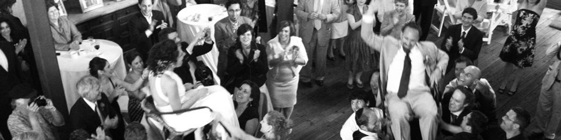 Black and white photo of a crowded gathering, possibly a party, with people mingling, and some raising their arms.