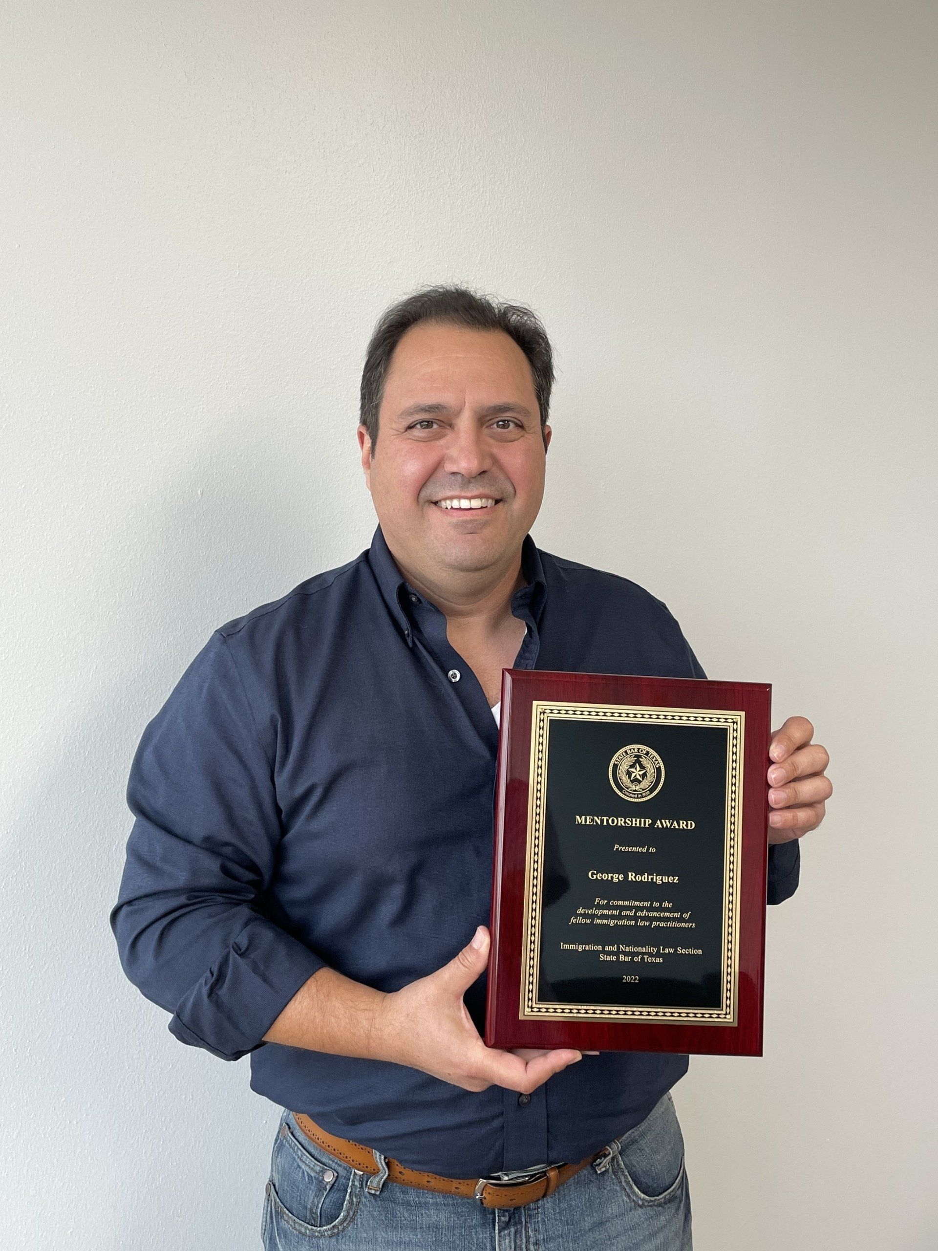 George holding the the Mentorship Award as the 2022 honoree from the State Bar of Texas' Immigration & Nationality Section.