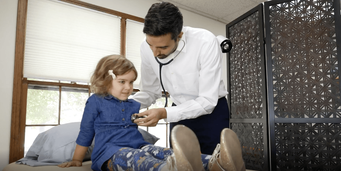 Professional photograph of a woman sitting in a chair and laughing with a cup of coffee.