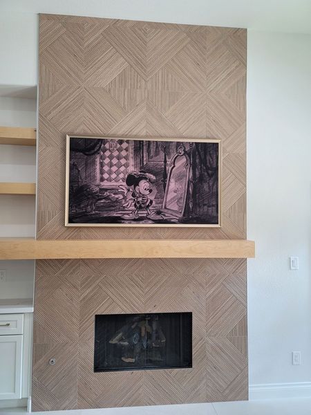 Fireplace wall with patterned paneling, a framed screen, and a wooden mantel.