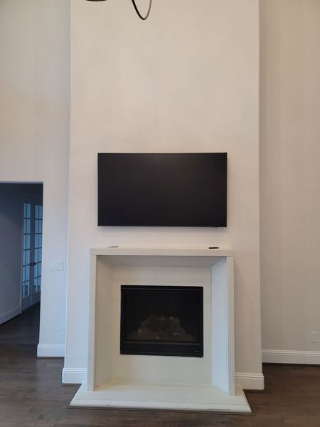 Fireplace with a black television mounted above it on a white wall.