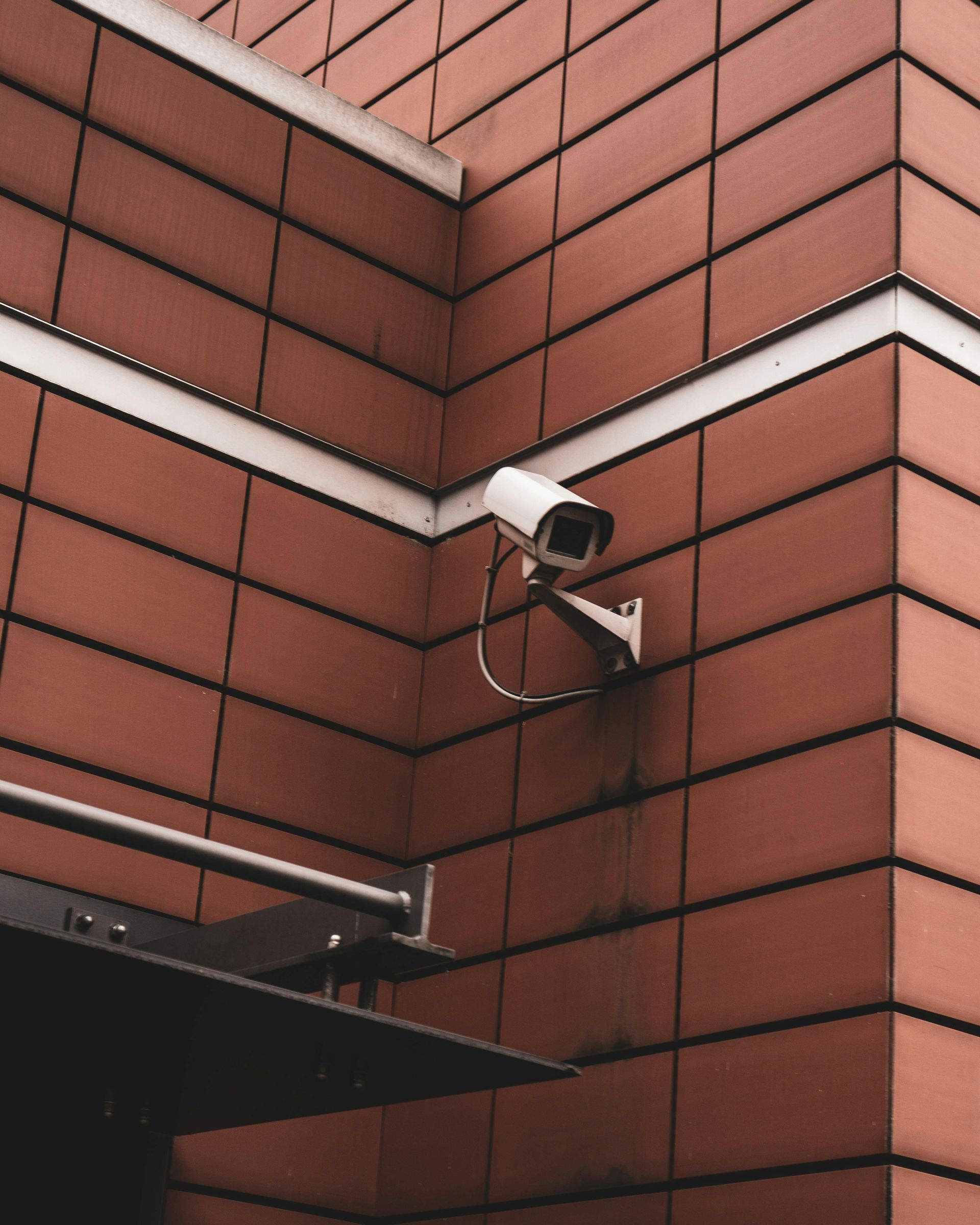 Security camera mounted on a reddish-brown tiled building corner.