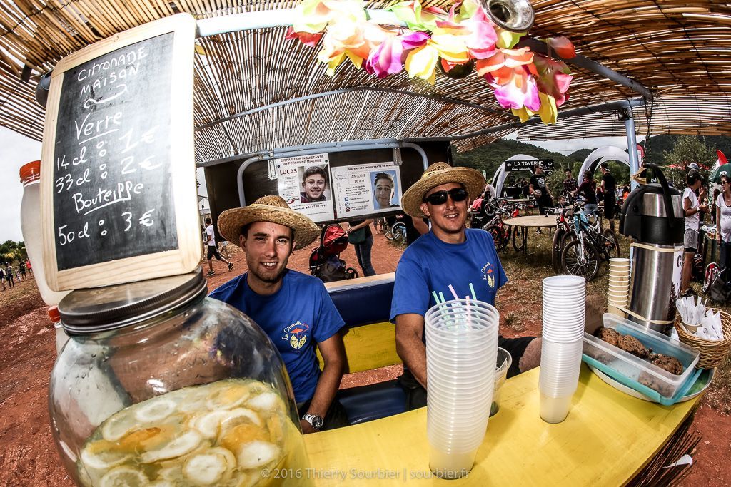 Deux hommes portant des chapeaux de paille sont assis à une table et vendent des boissons.