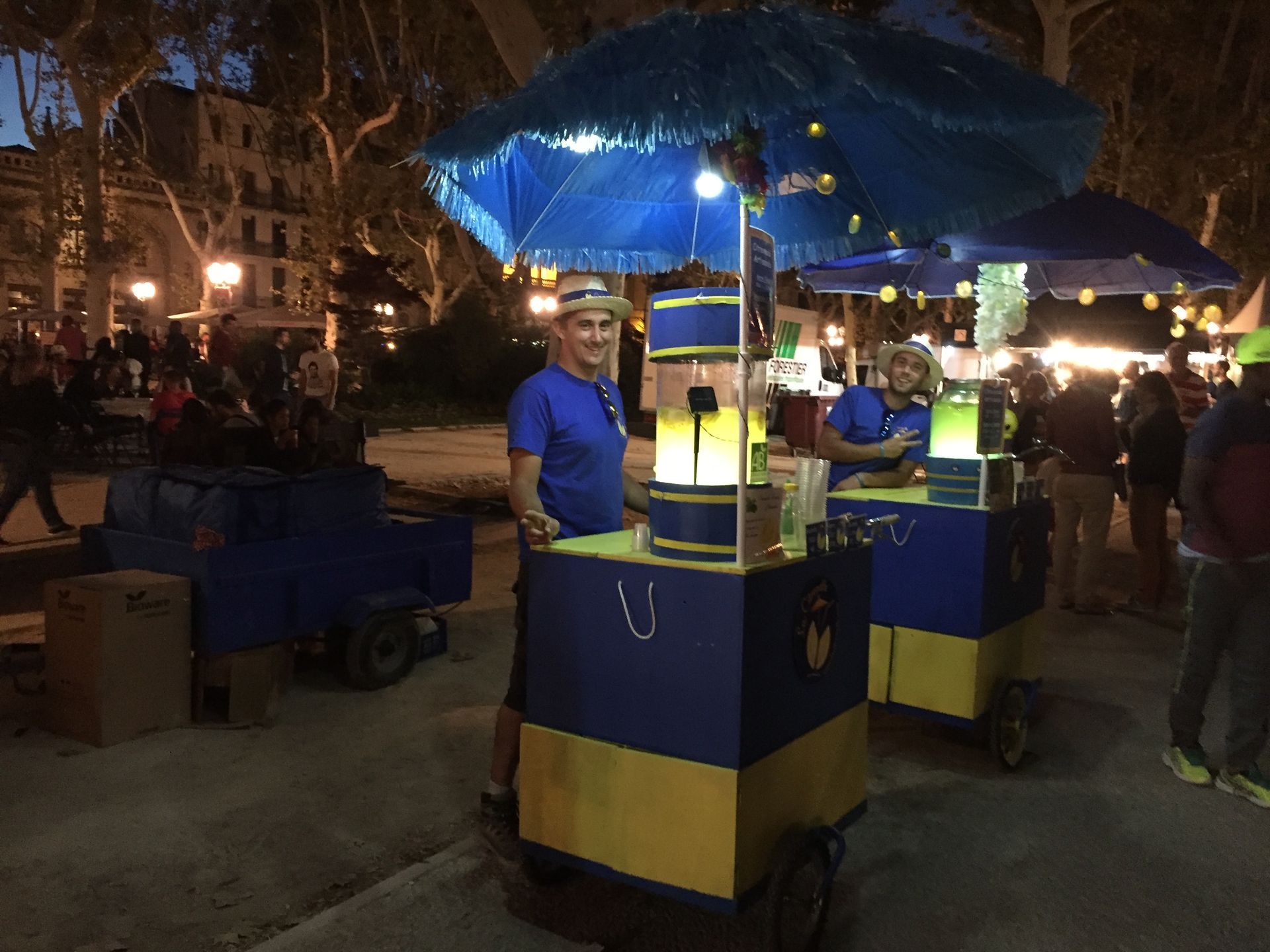 Un homme en chemise bleue se tient devant un chariot bleu et jaune