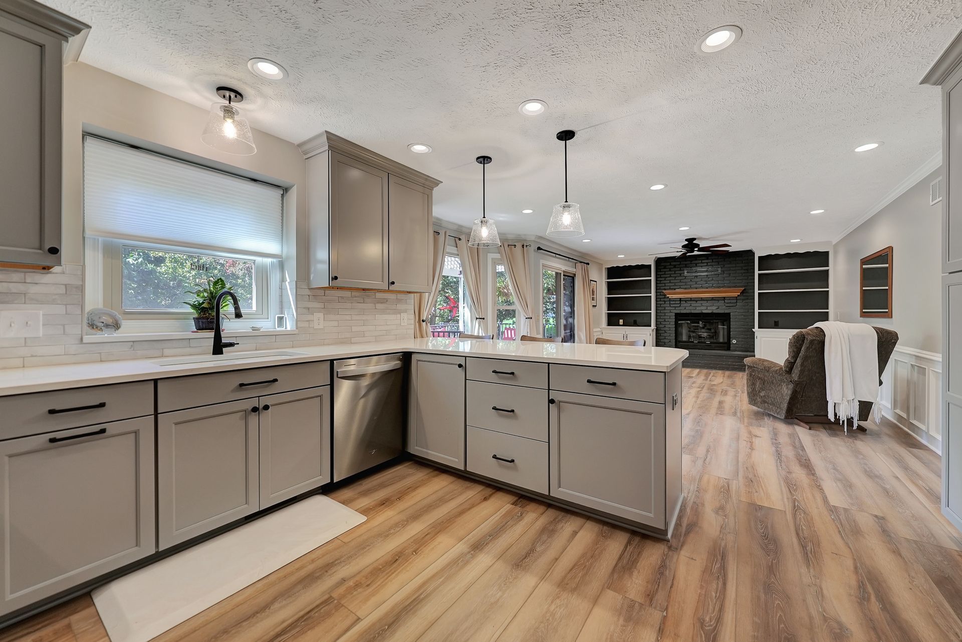 Remodeled Kitchen and Living Room with new cabinets, a black faucet, and painted brick.