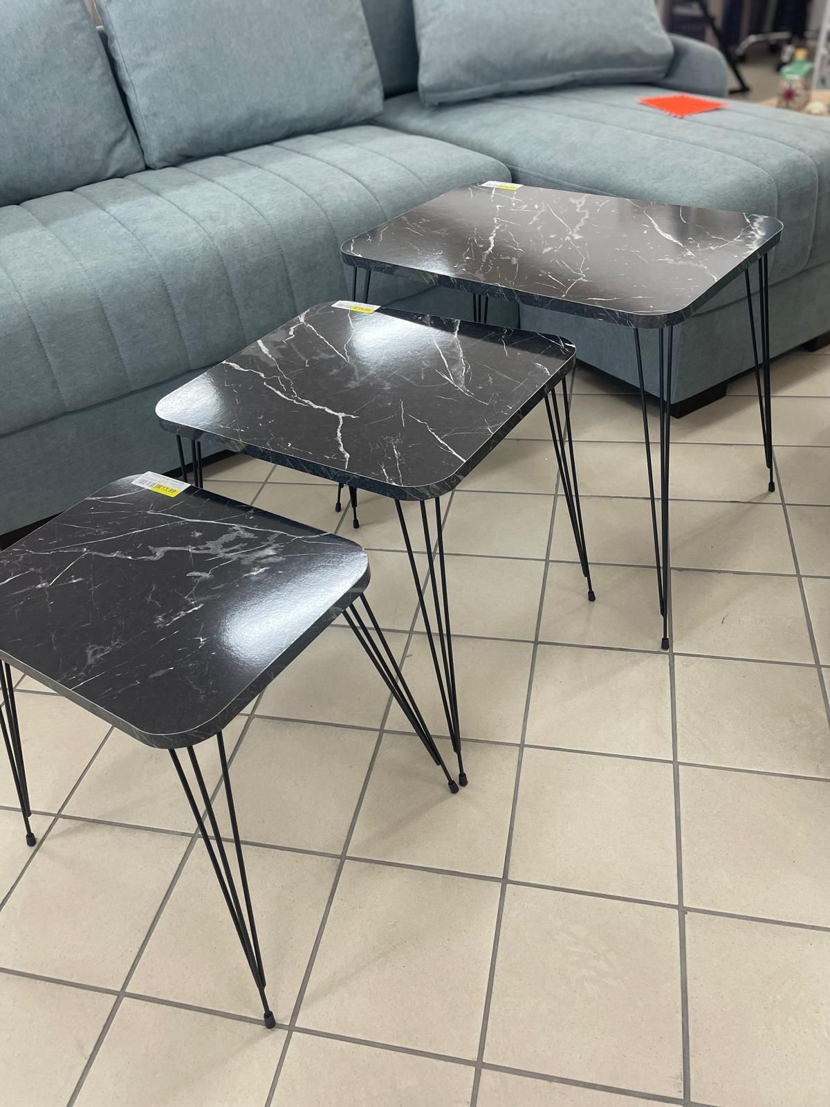 Tre tavoli sono appoggiati su un pavimento piastrellato di fronte a un divano.