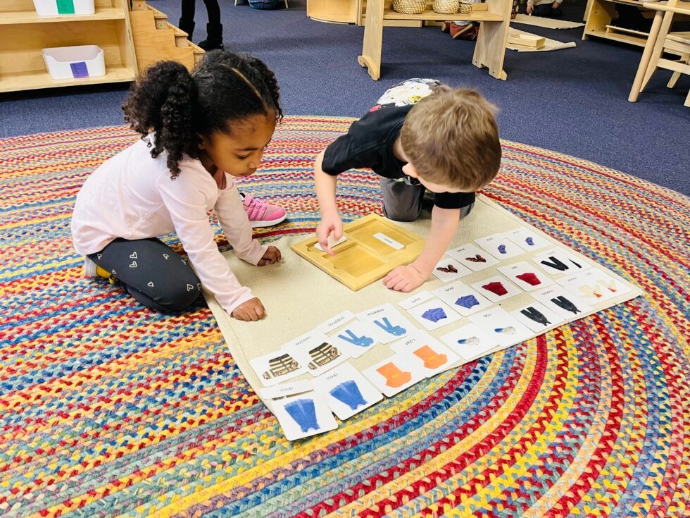 Montessori children are working with cards on the floor