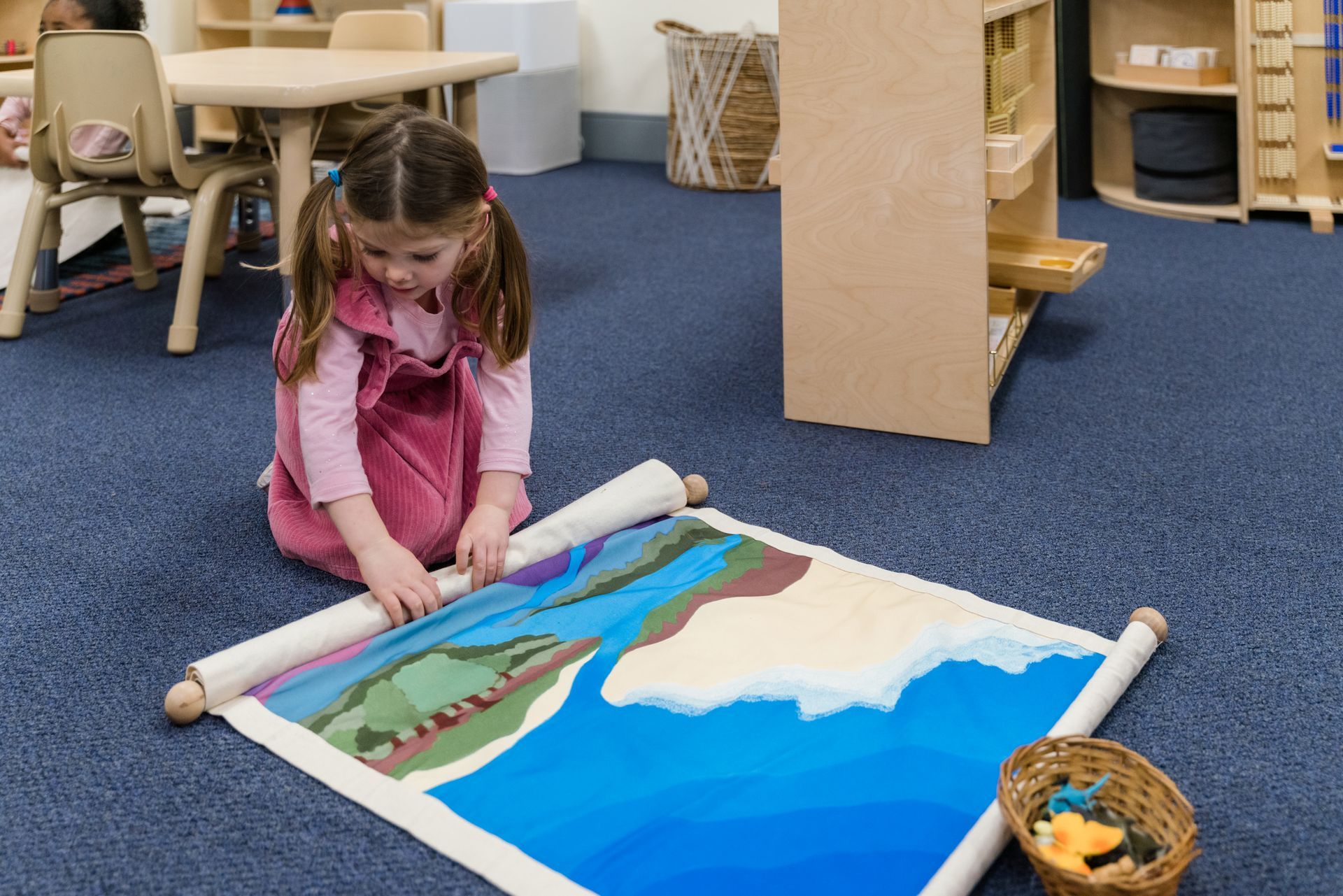A montessori child is sitting on the floor working with materials.