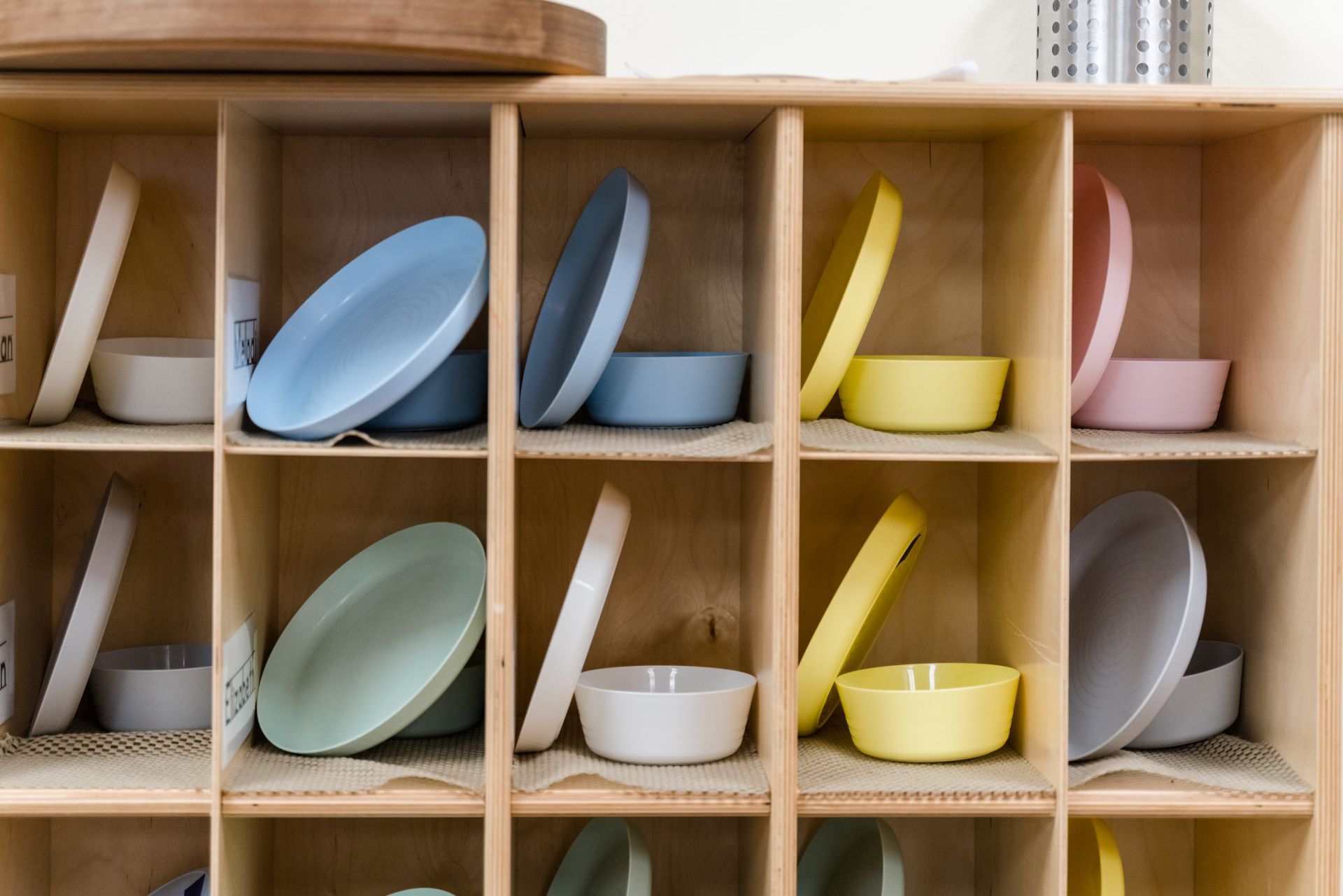 A shelf filled with plates and bowls of different colors.