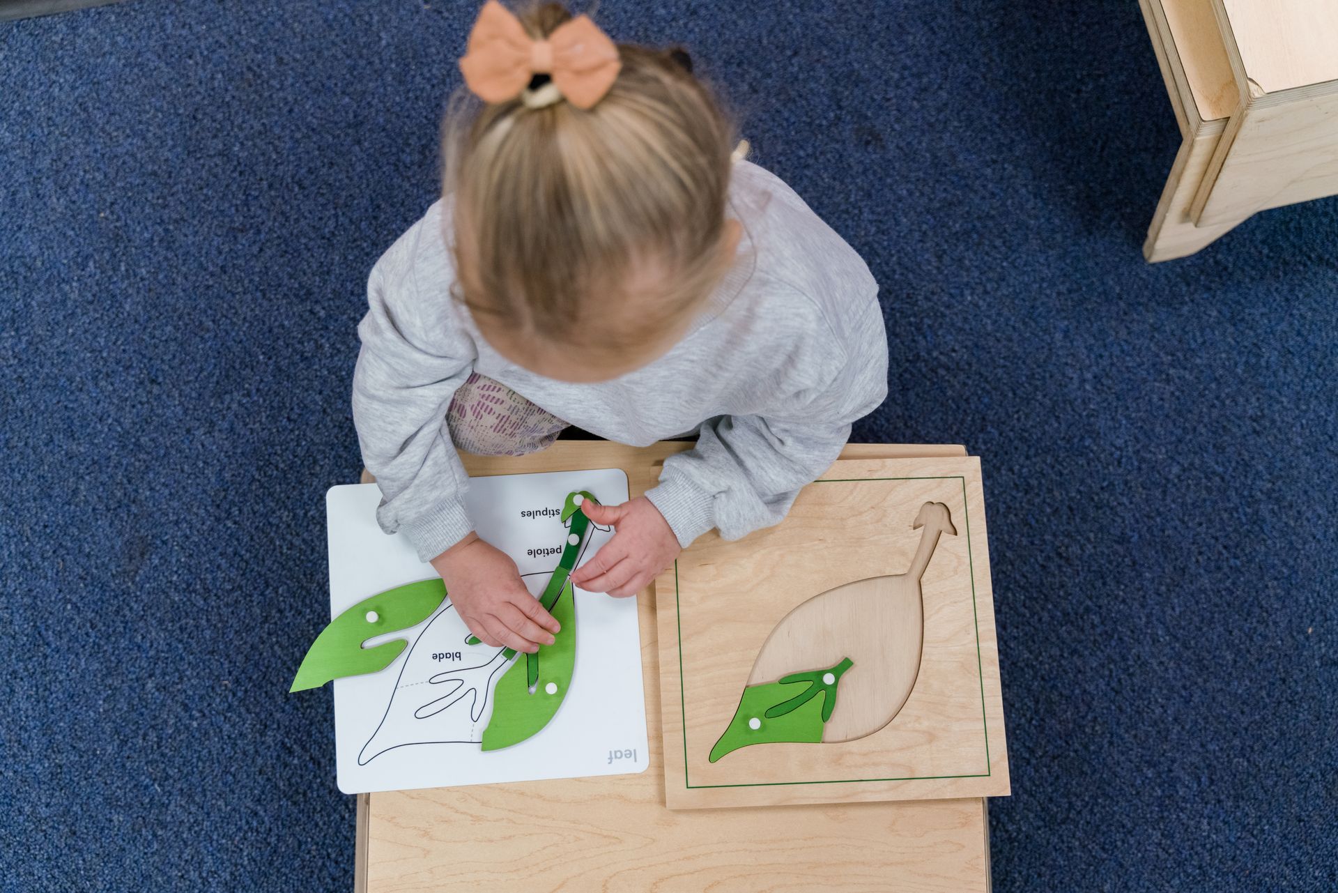 A montessori child is sitting at a table working with a puzzle.
