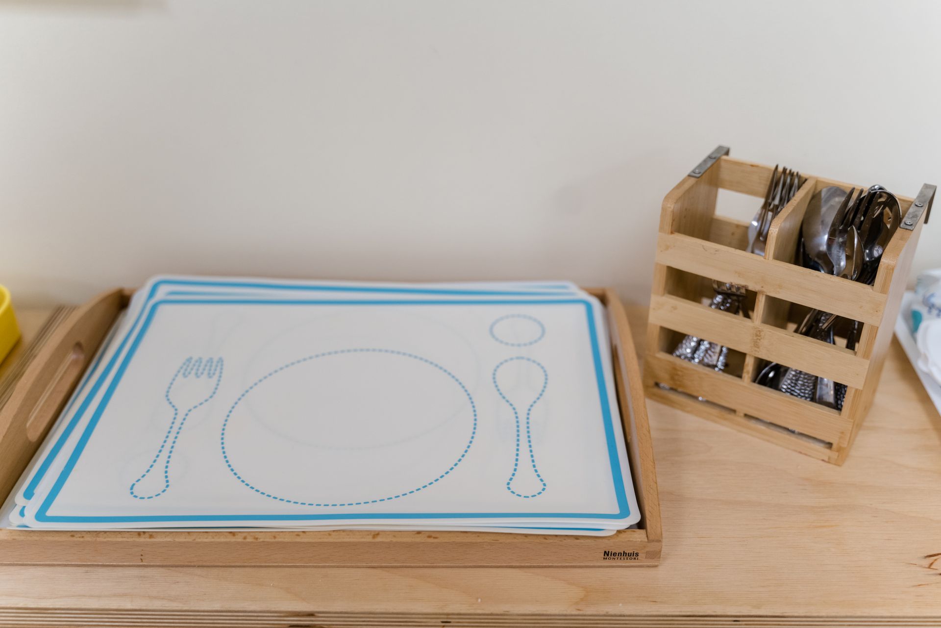 A wooden tray with a plate, fork and spoon on it.