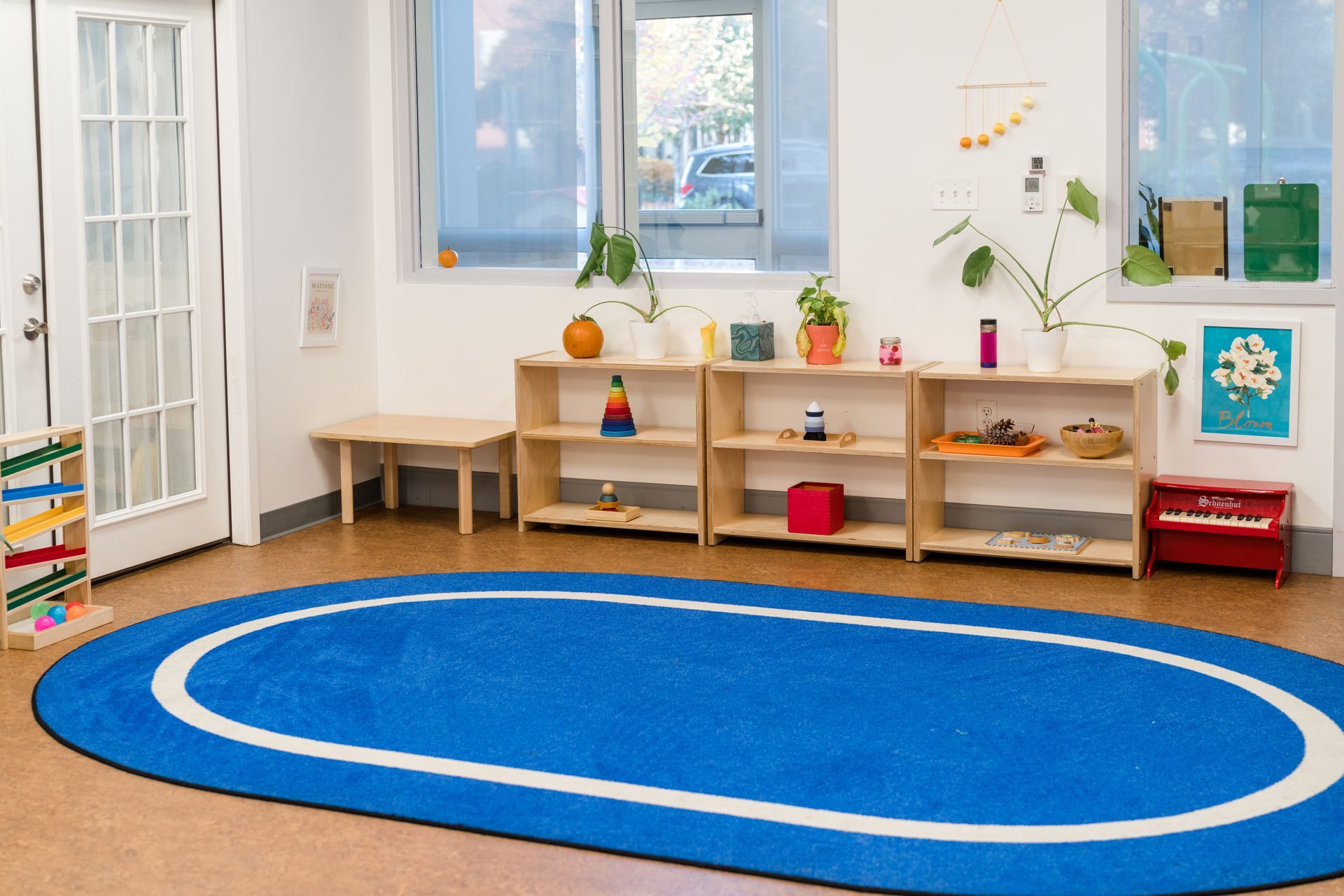There is a blue rug in the middle of the montessori room.