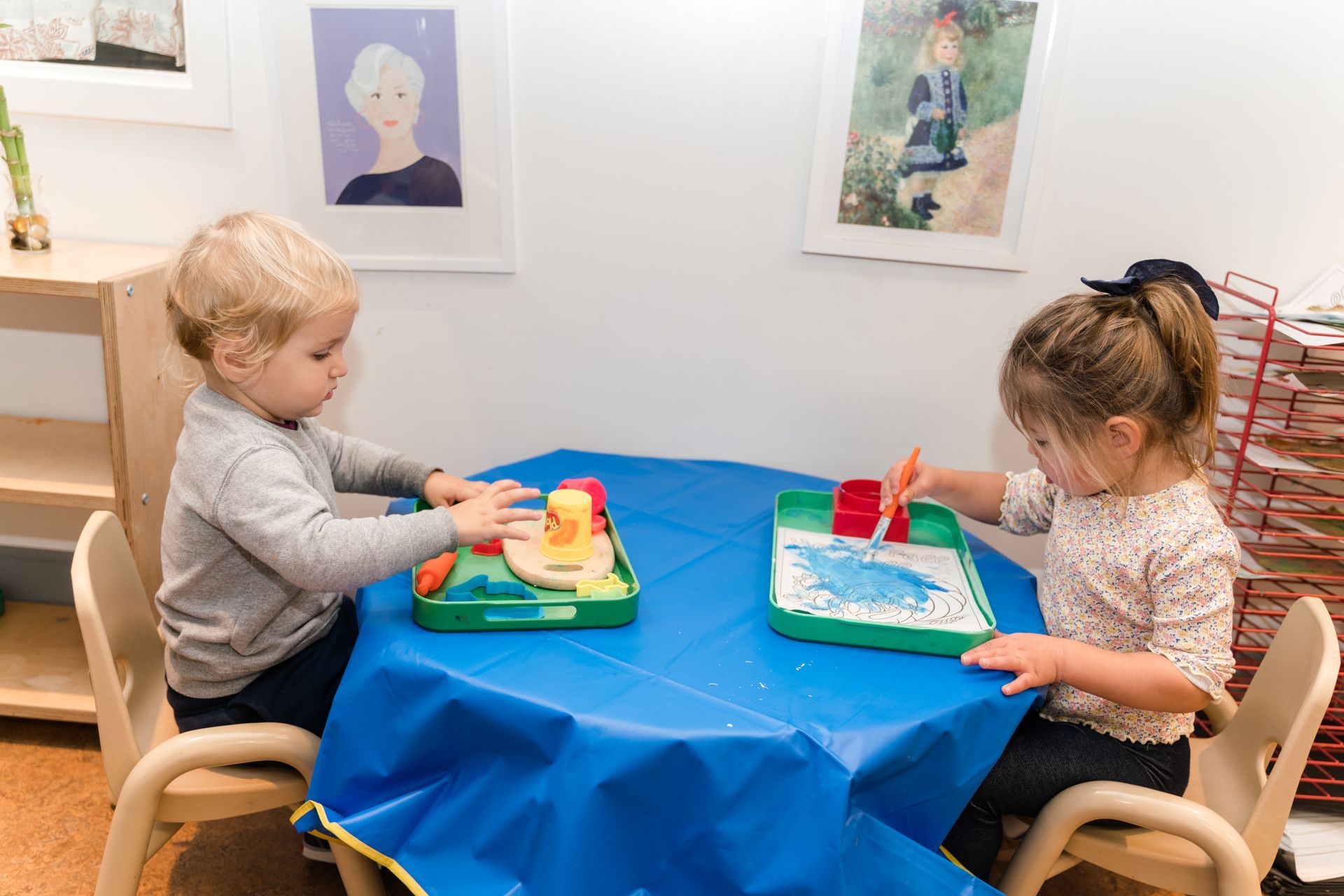 Two montessori children are sitting at a table working with materials.