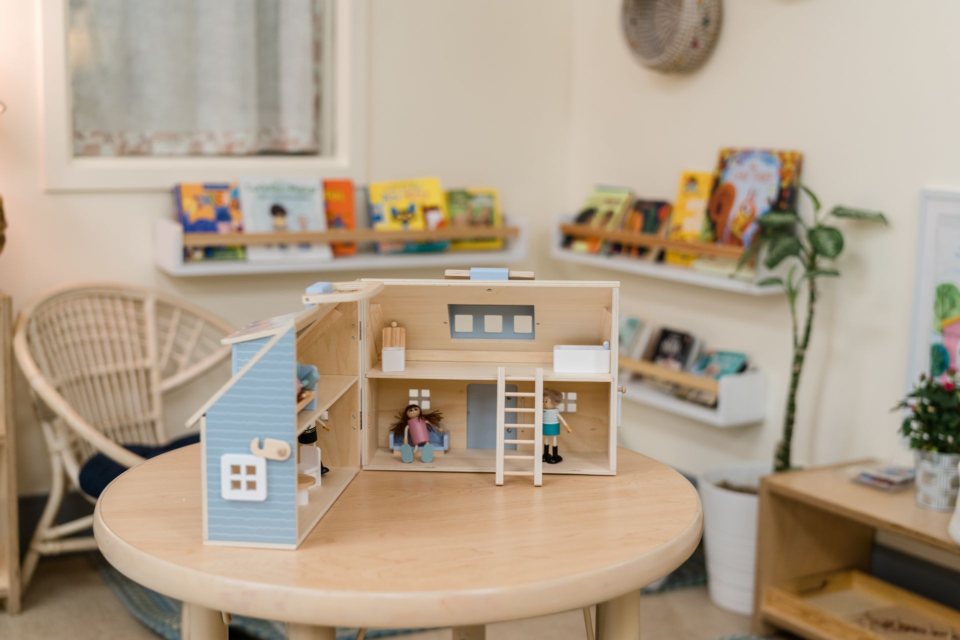 A doll house is sitting on a wooden table in a room.