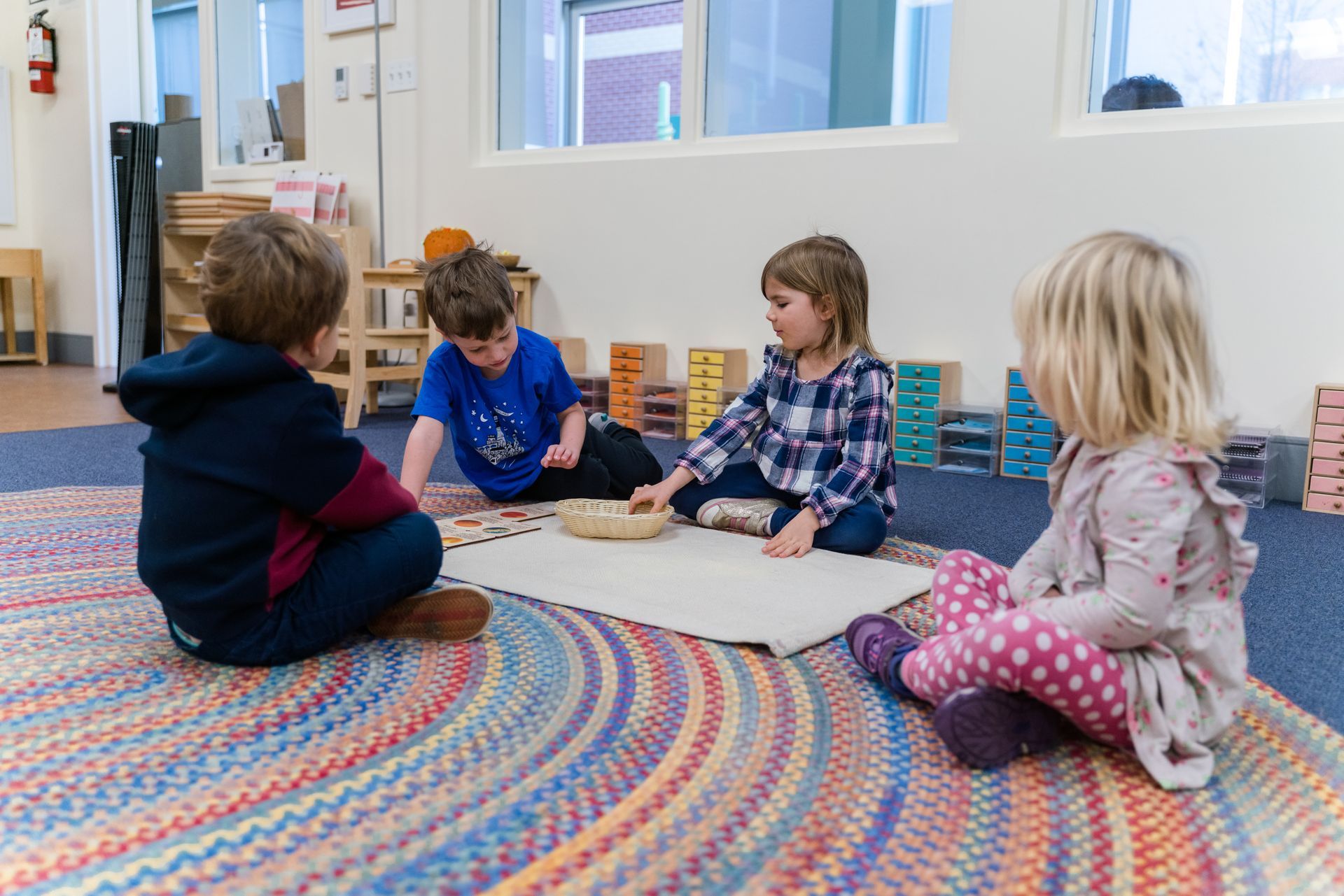 A group of montessori children are sitting on the floor working with blocks.