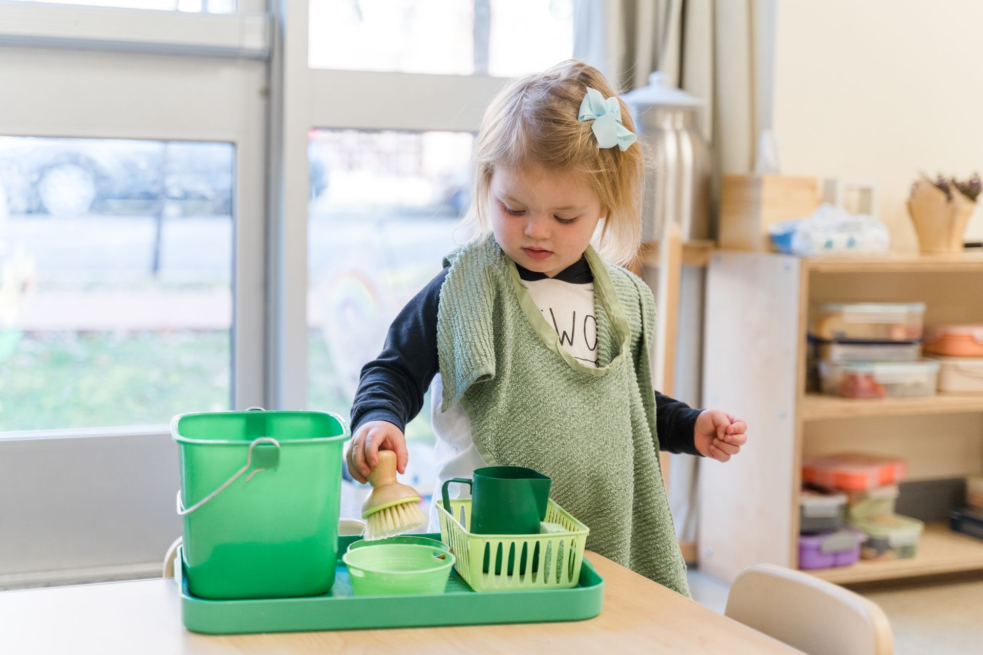 Montessori child is playing with cleaning supplies at a table