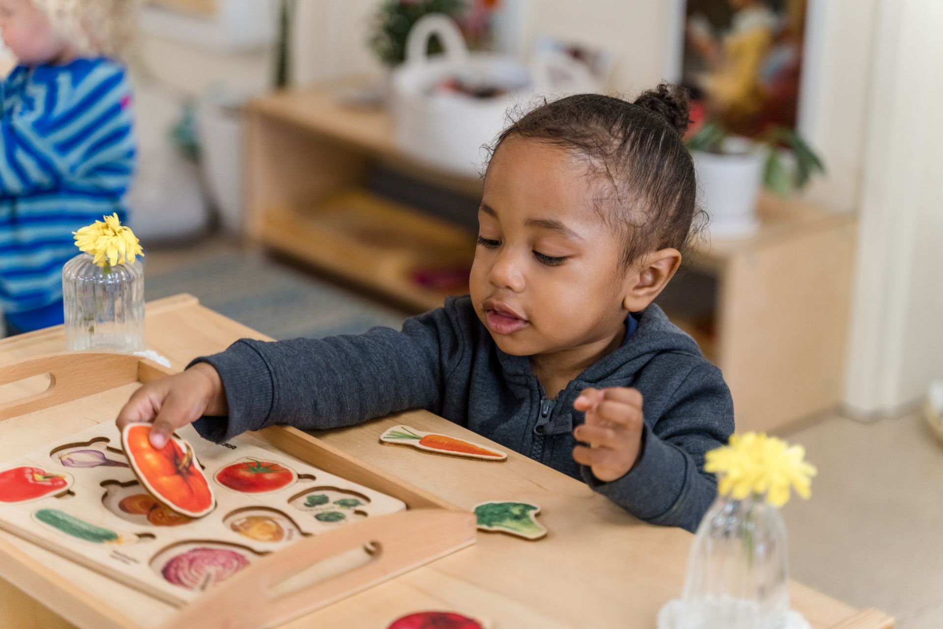 A montessori child is sitting at a table working with a puzzle.