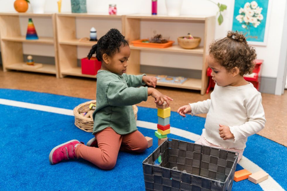 Montessori children are working with blocks on the floor in a classroom